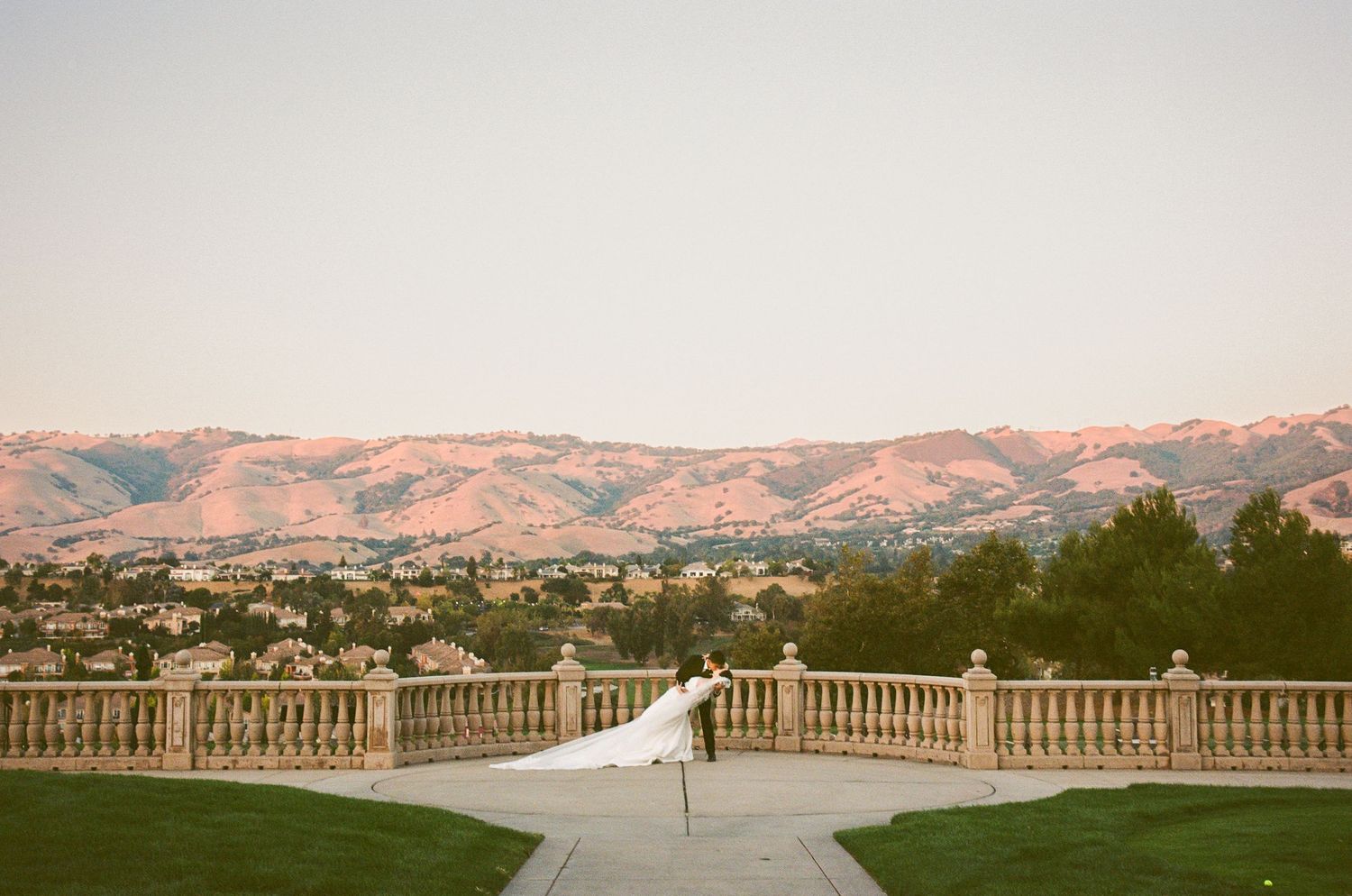 Panoramic mountain landscape view from a white balcony during golden hour.