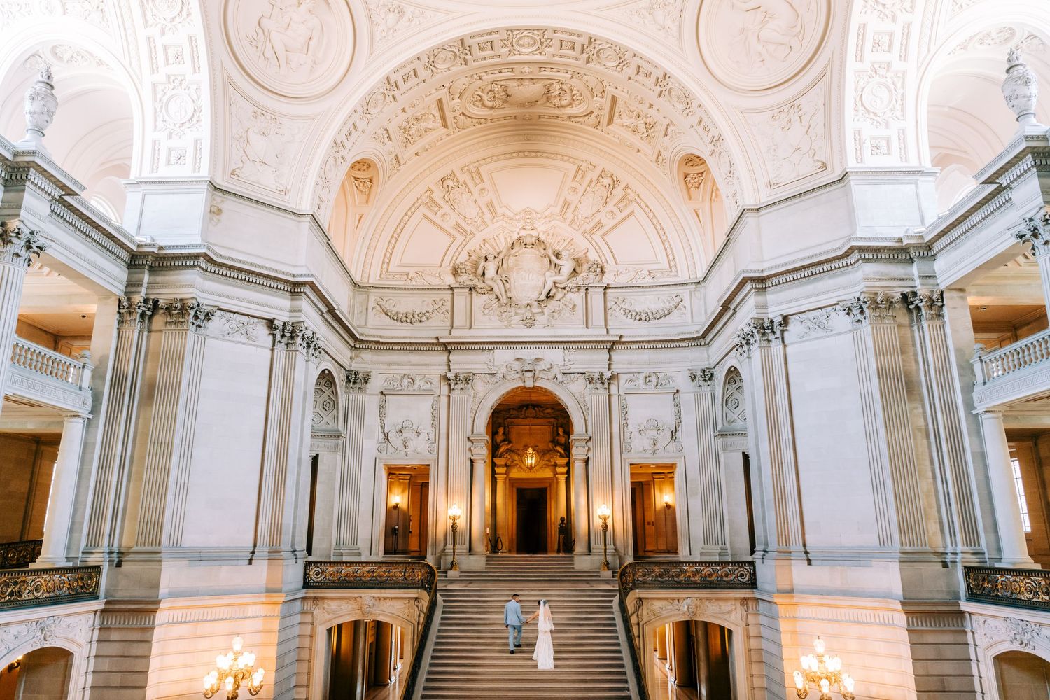 An elegant Beaux-Arts style interior with curved staircases and vaulted ceiling.