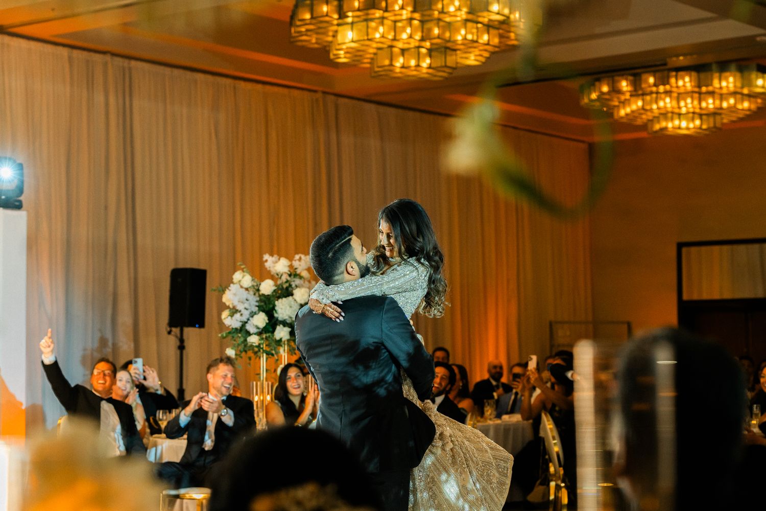 Elegant ballroom reception with warm amber lighting and crystal chandeliers.