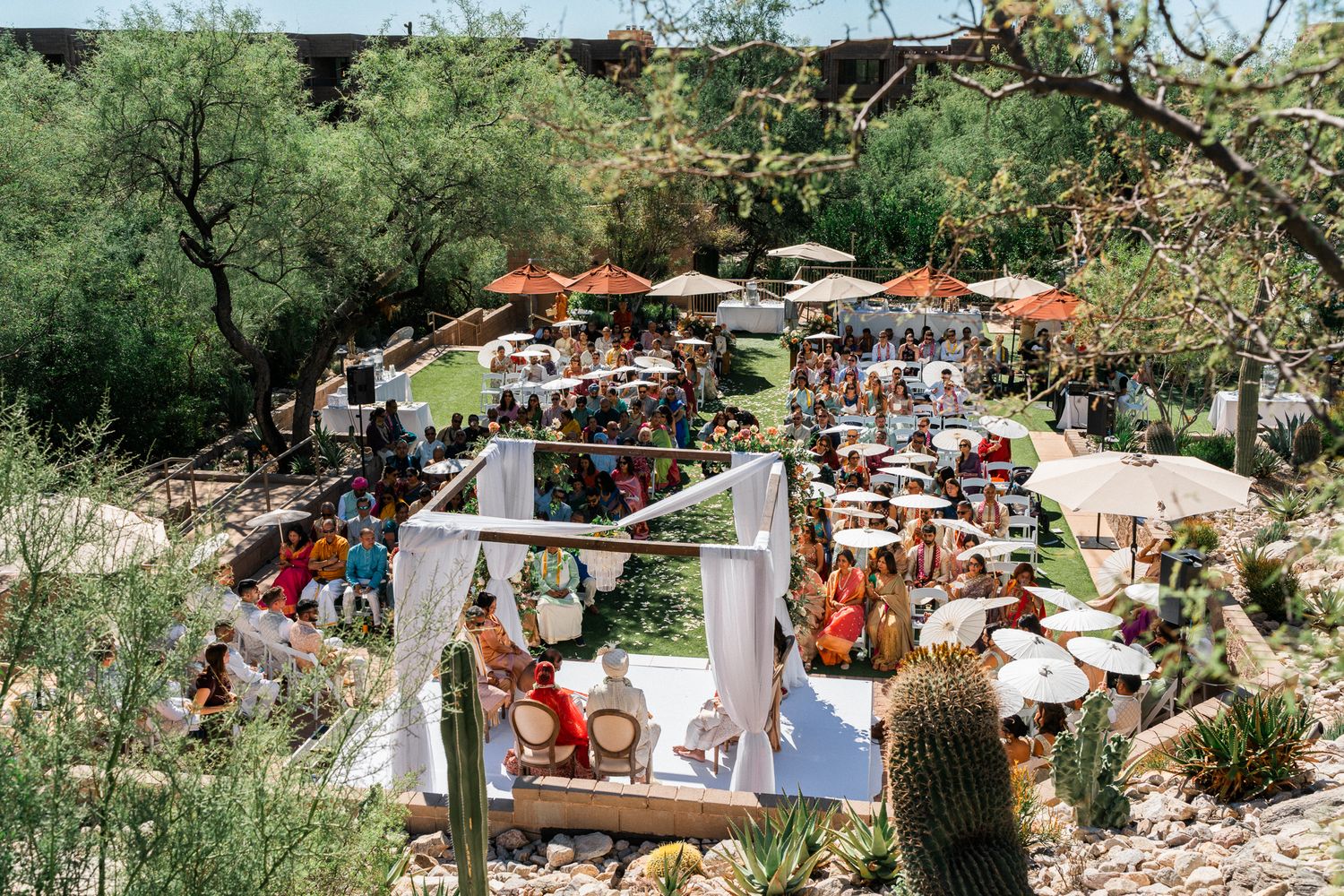 Aerial view of an outdoor wedding reception with colorful table settings and natural decor.