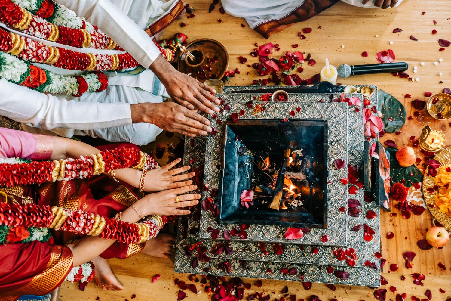 Traditional wedding ceremony details with henna decorated feet and rose petals on wooden floor.