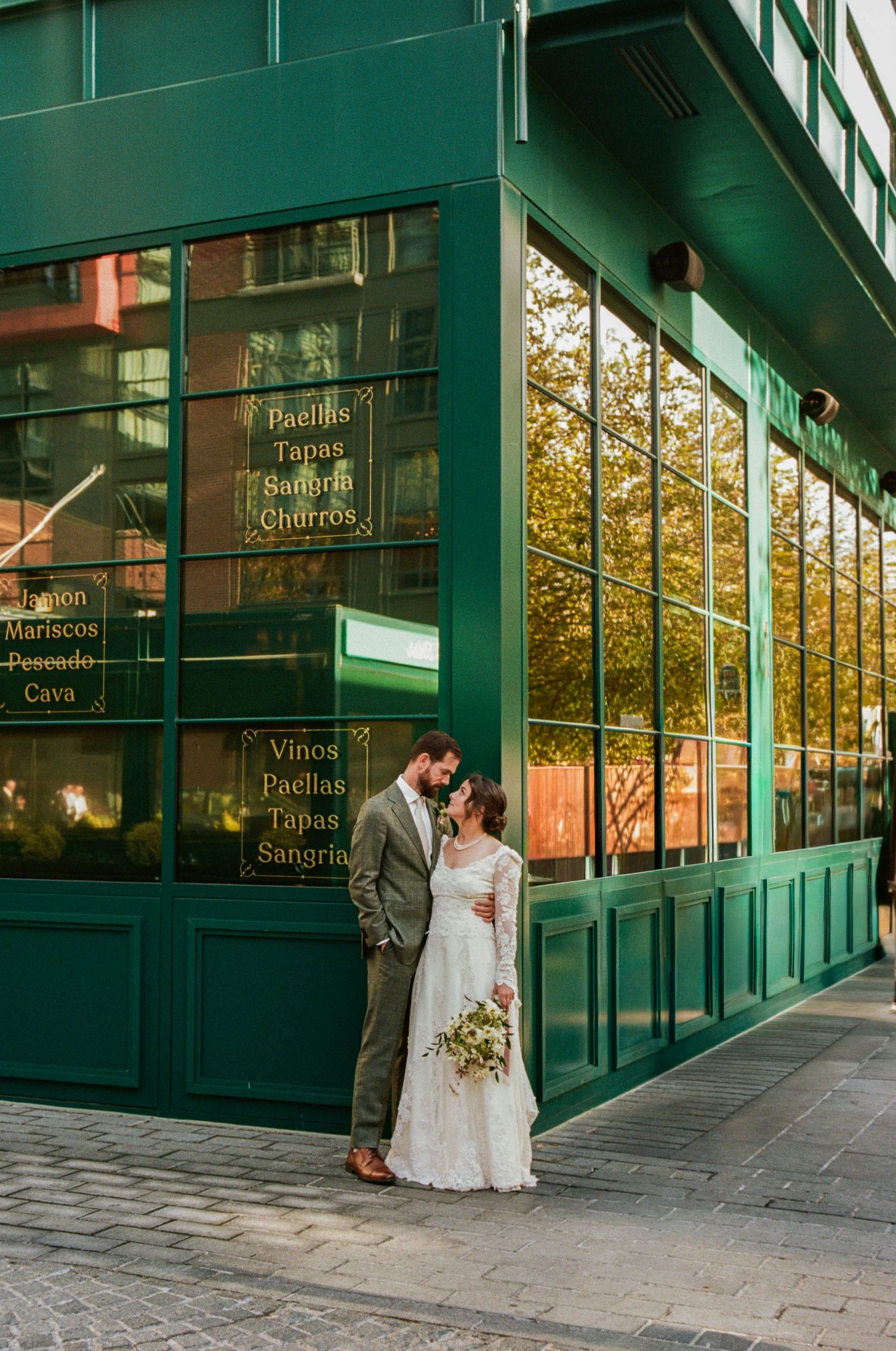 Modern green-framed building exterior creates architectural backdrop for wedding photography.