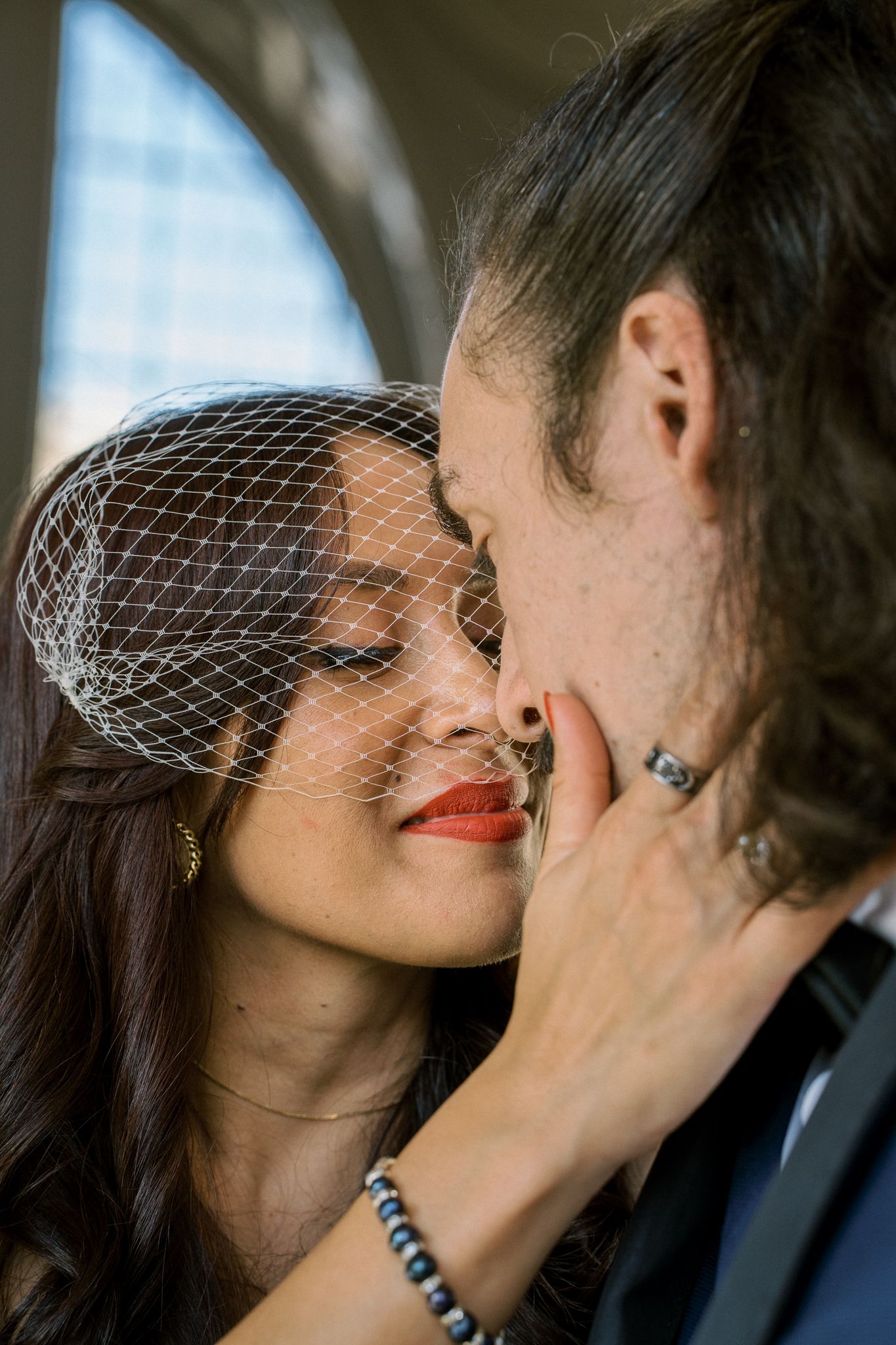 An intimate wedding portrait showing tender affection in an architectural setting.