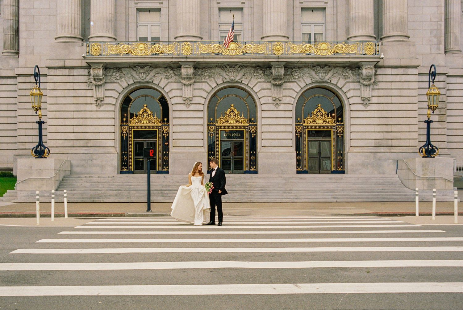 Bride and groom share a romantic moment at a crosswalk in front of San Francisco City Hall.