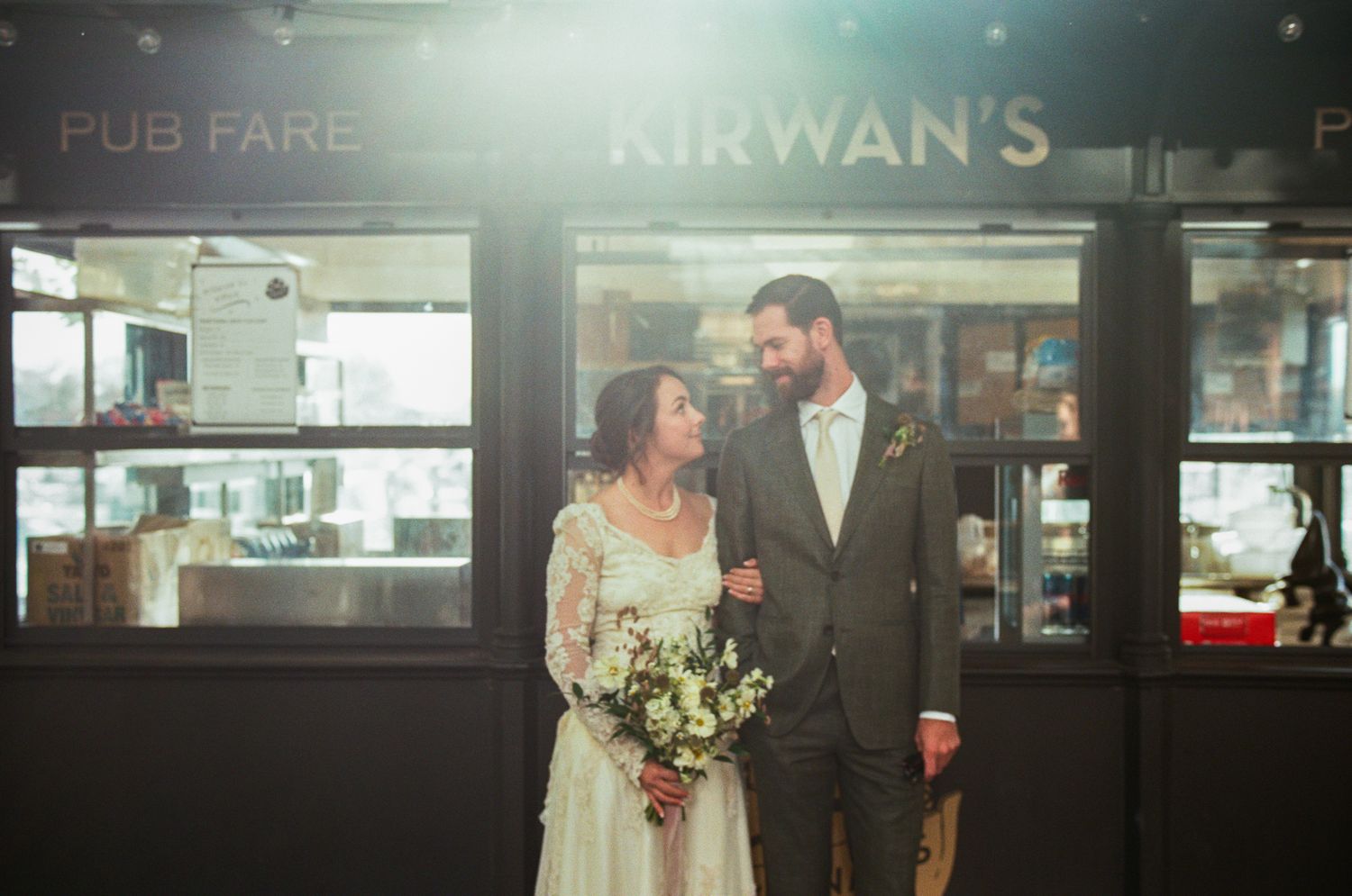 Urban wedding photos outside storefront with vintage signage.