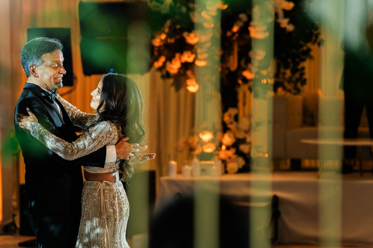 Romantic dance scene in a warmly lit ballroom with string lights overhead.