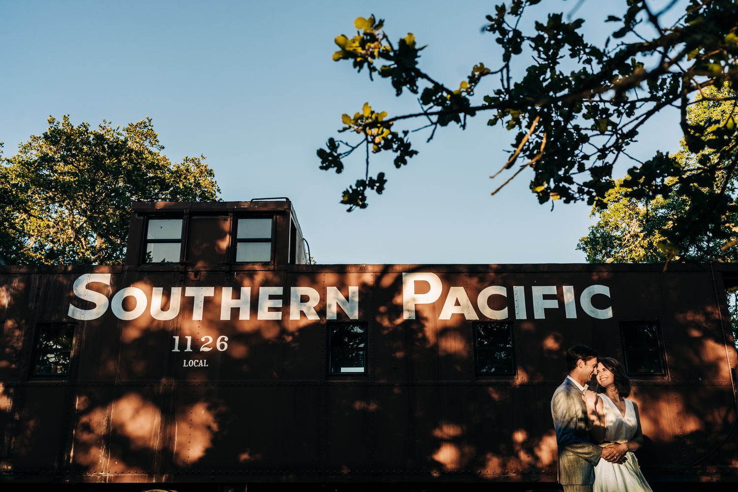 Vintage Southern Pacific railway sign visible through tree branches against blue sky.
