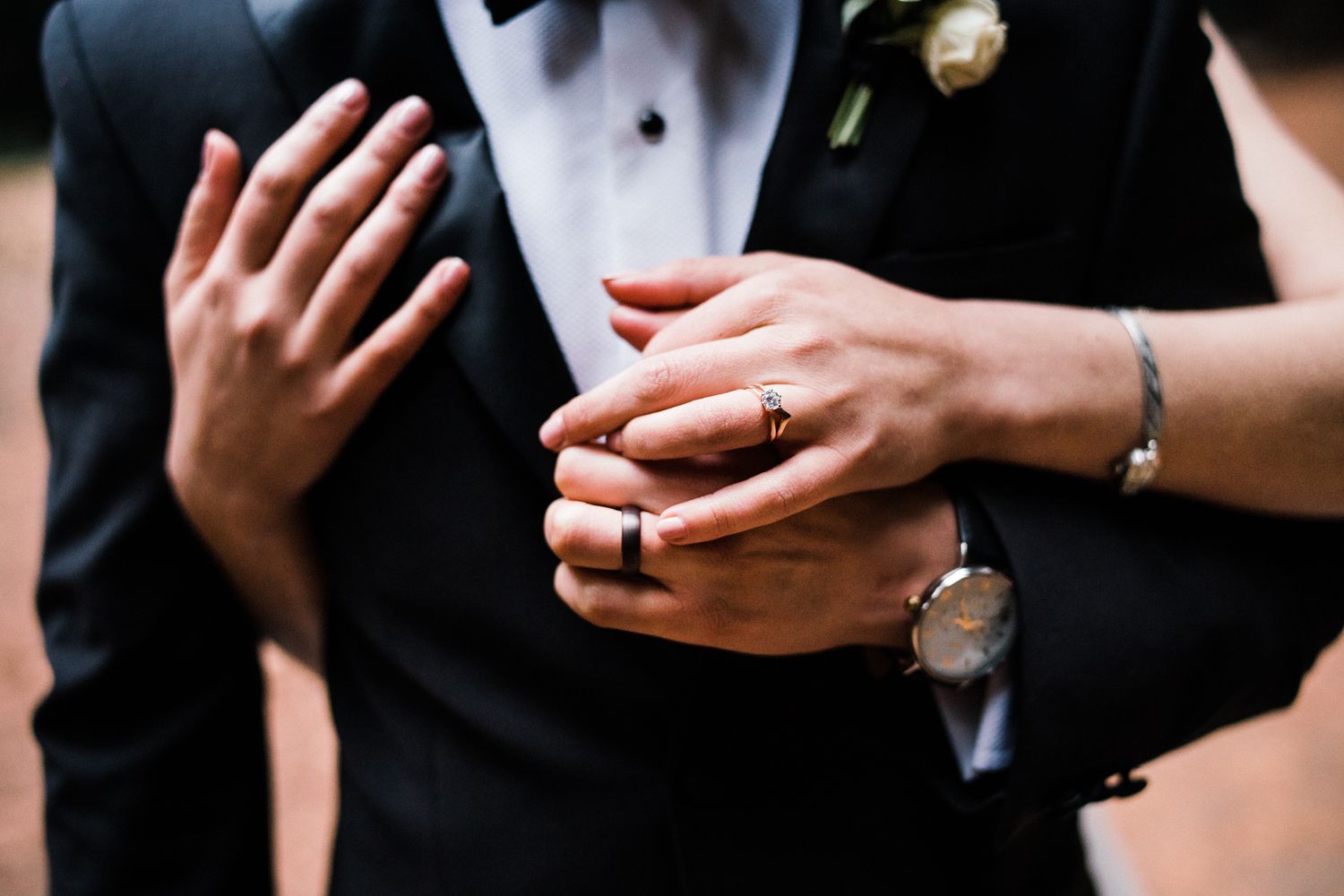 Close-up details of wedding rings and hands in black and white.