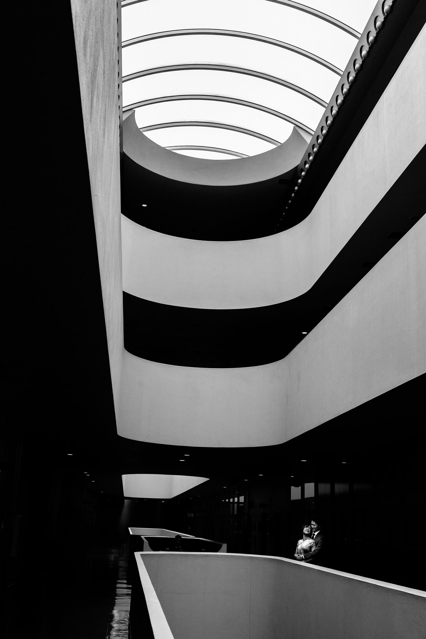 Black and white interior of the Guggenheim Museum featuring spiral ramps and a stunning skylight ceiling.
