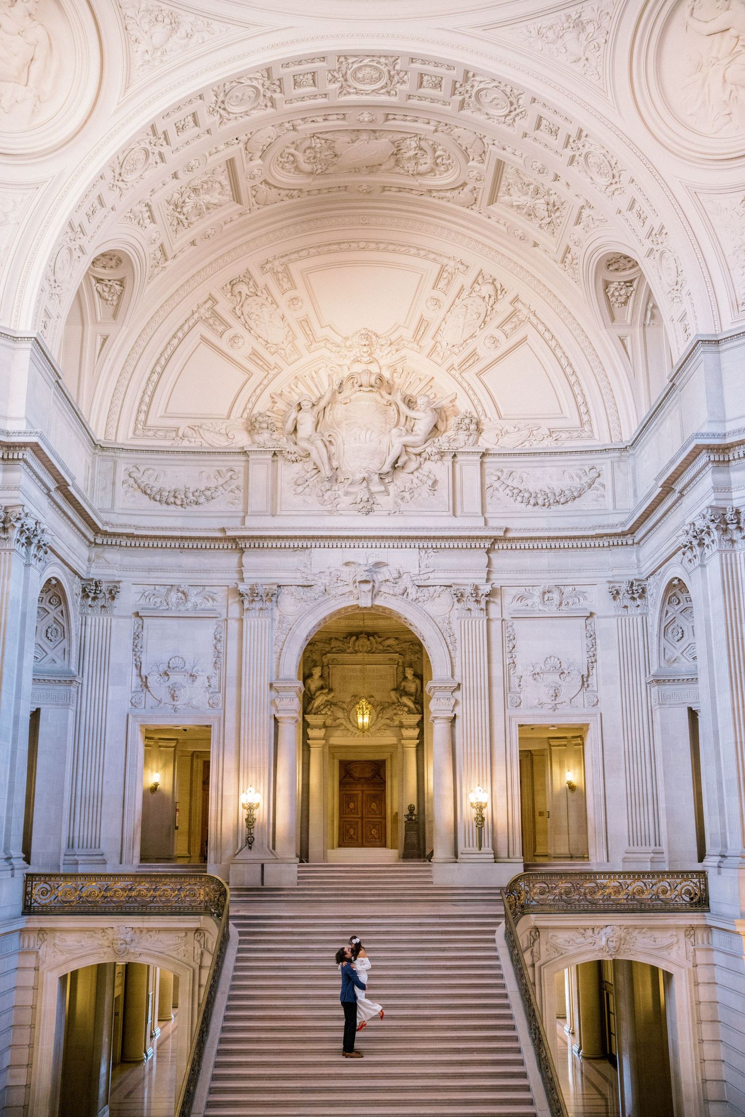 Ornate white marble staircase and grand interior architecture of a historic palace with baroque decorative elements.