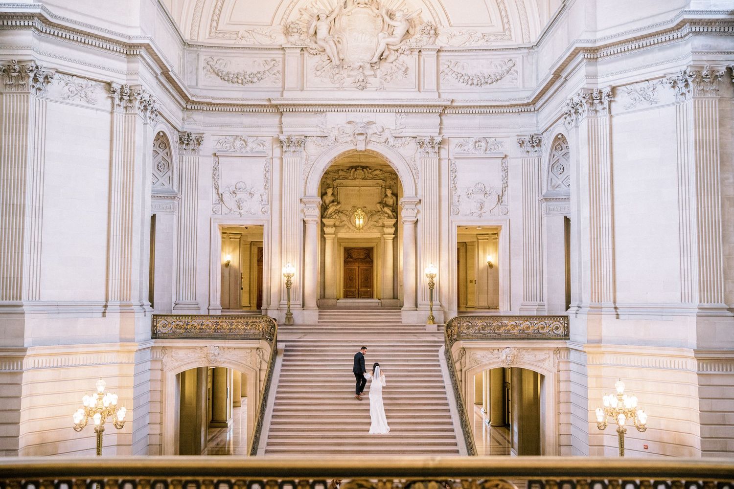 Bride and groom share a romantic moment on the grand staircase of San Francisco City Hall.