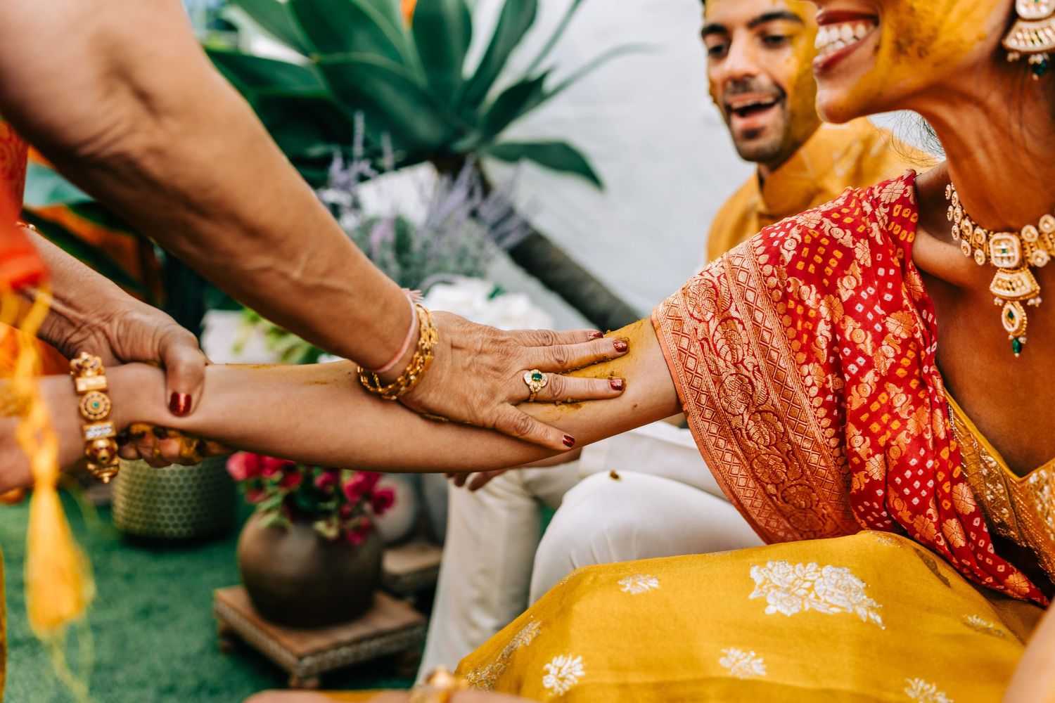Close-up shots of hands performing traditional Indian wedding rituals with turmeric.