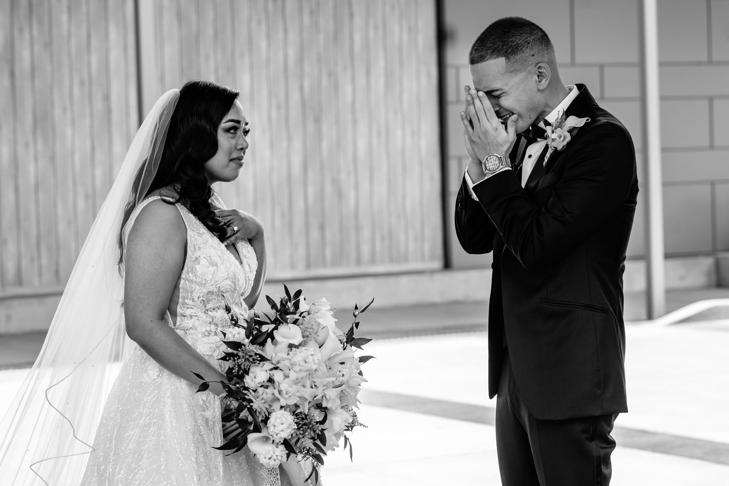 Groom covers his mouth in emotional reaction seeing bride in wedding dress during first look ceremony.