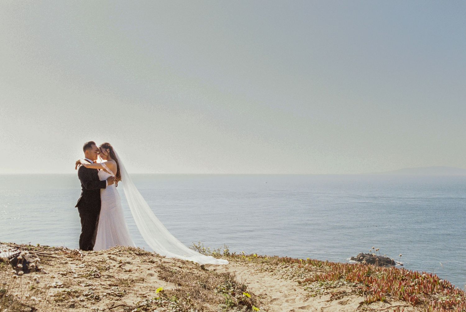 Romantic wedding photos taken on a scenic coastal cliff overlooking the ocean.
