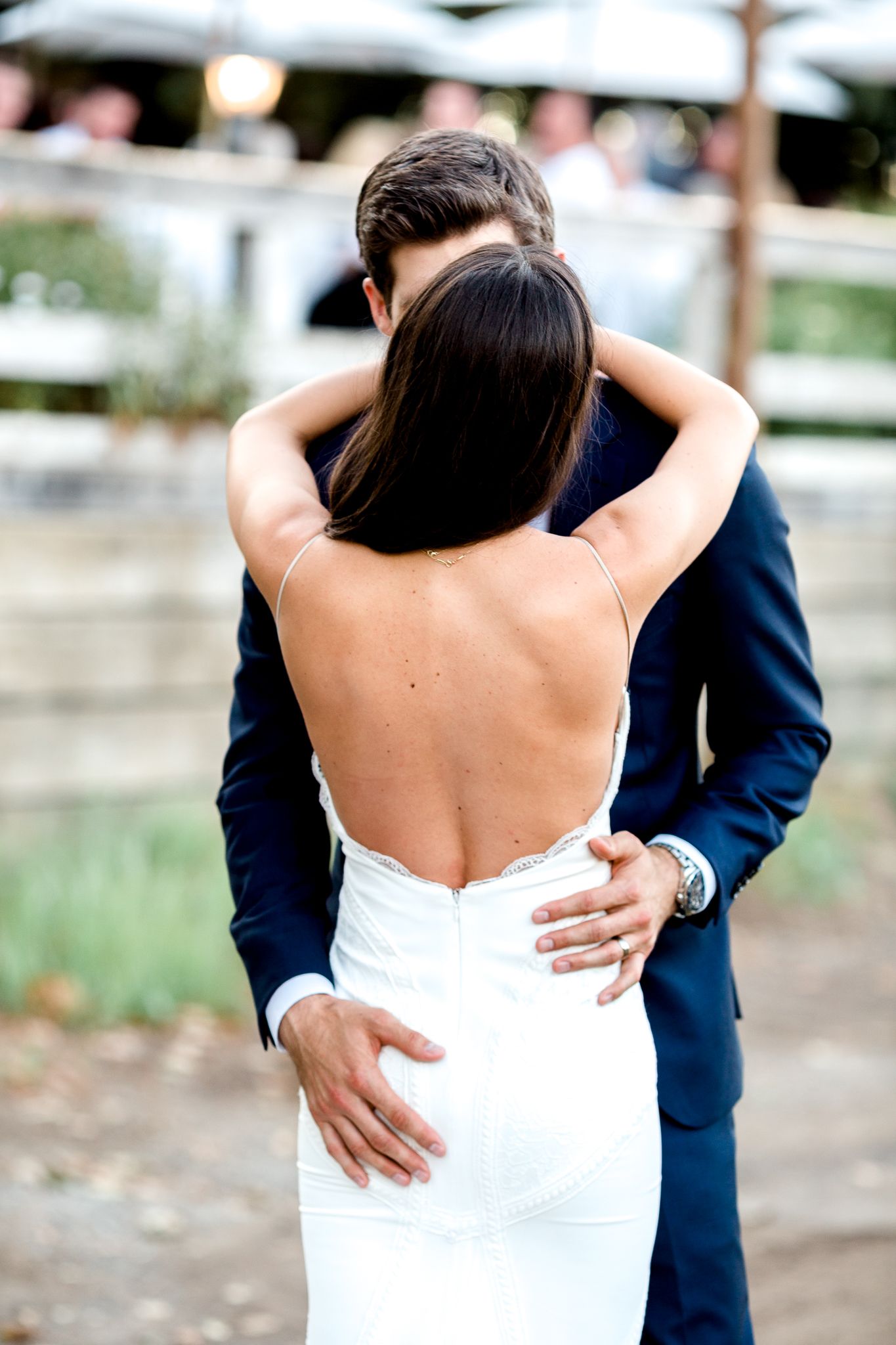 Intimate wedding photos showing the back of a strapless white gown and navy suit.