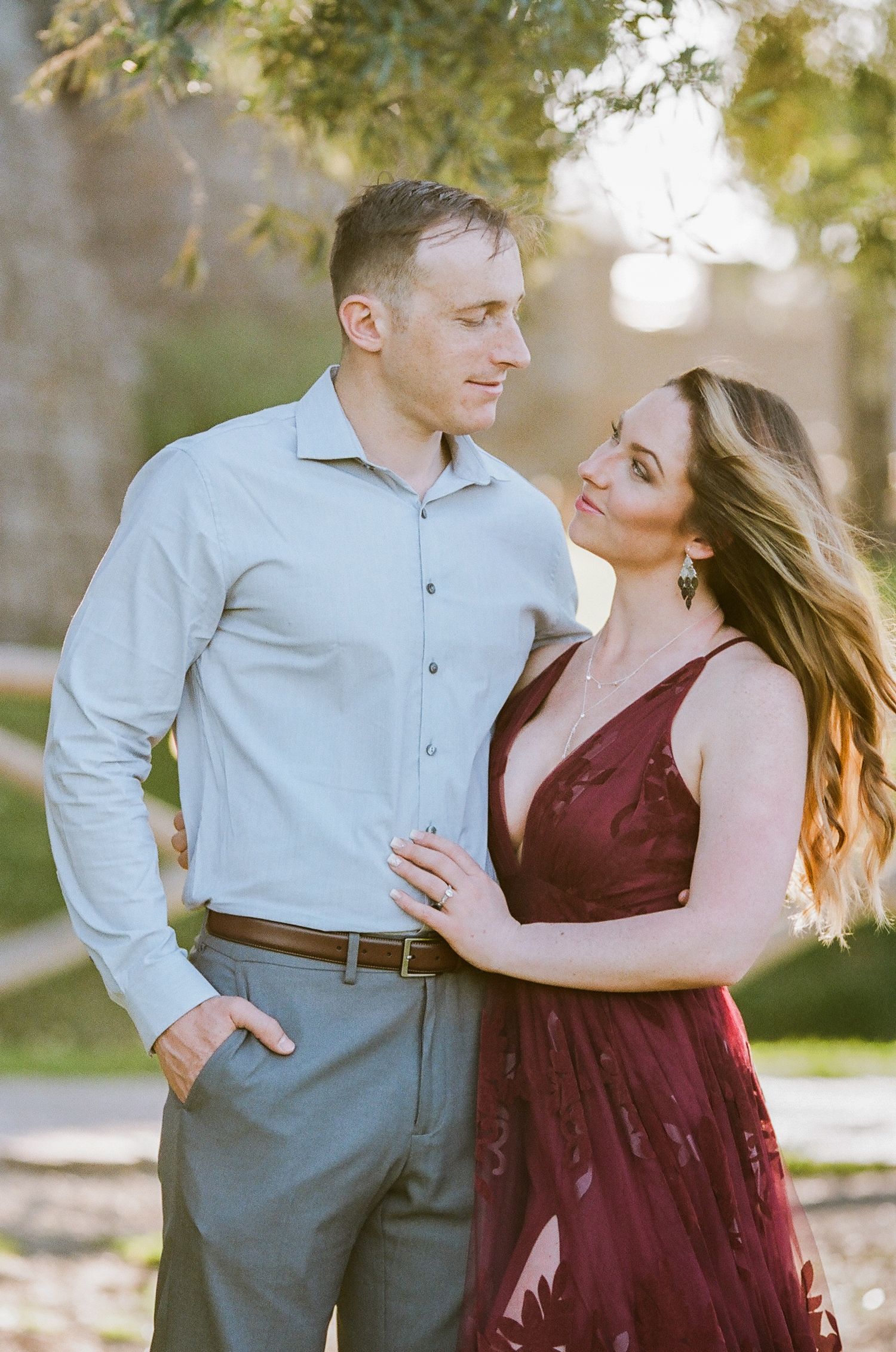 Romantic engagement photos in a park during golden hour.