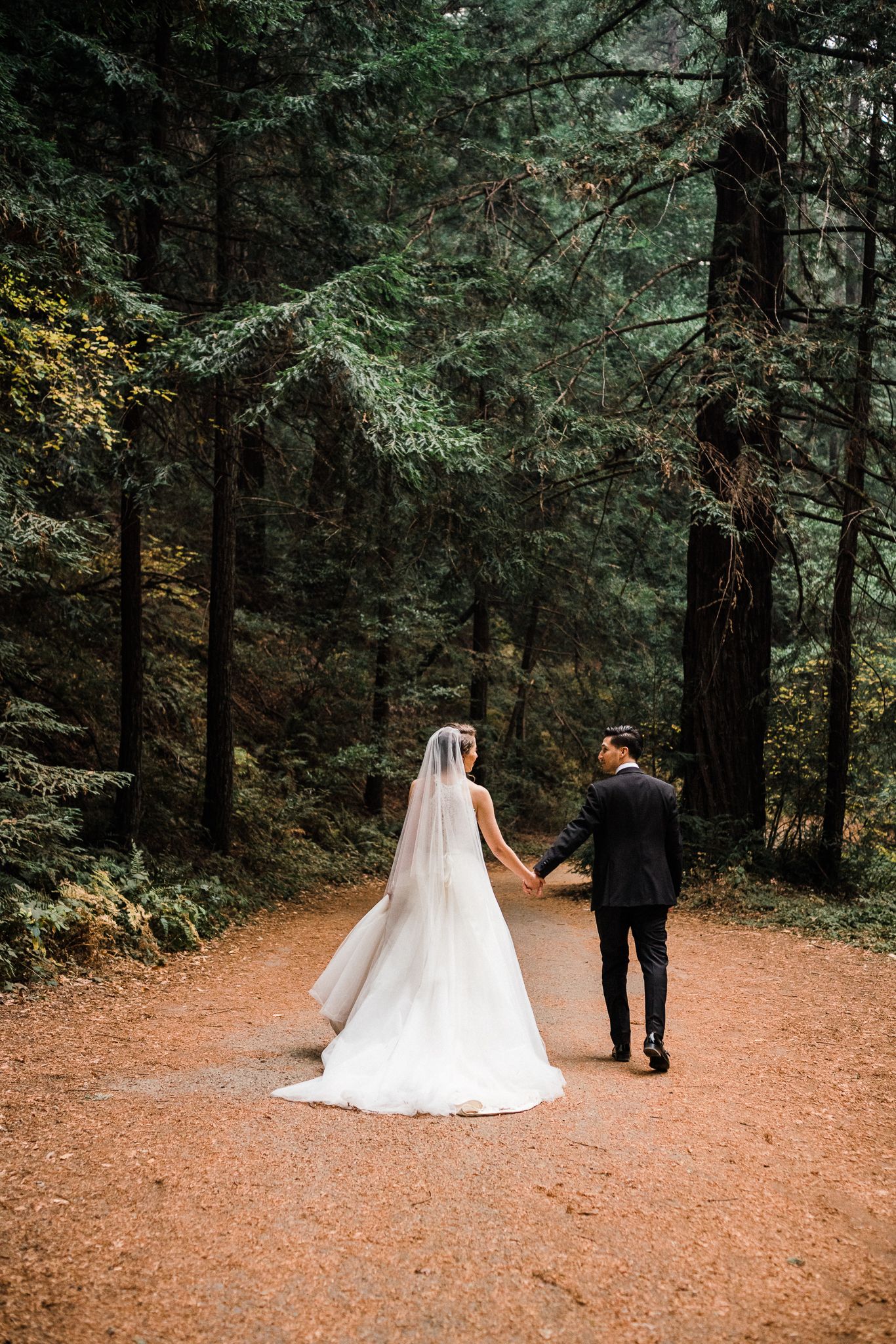 A romantic first look sequence in a forest with a flowing white wedding dress and dark suit.