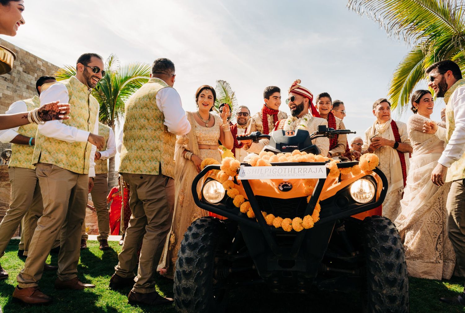 Outdoor wedding celebration with orange floral decorations and a vintage orange car.