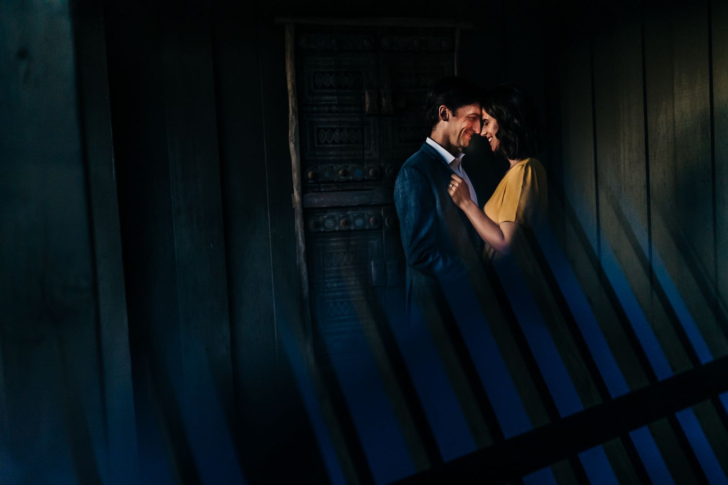 Moody evening scene with dark wooden walls and dramatic shadows.