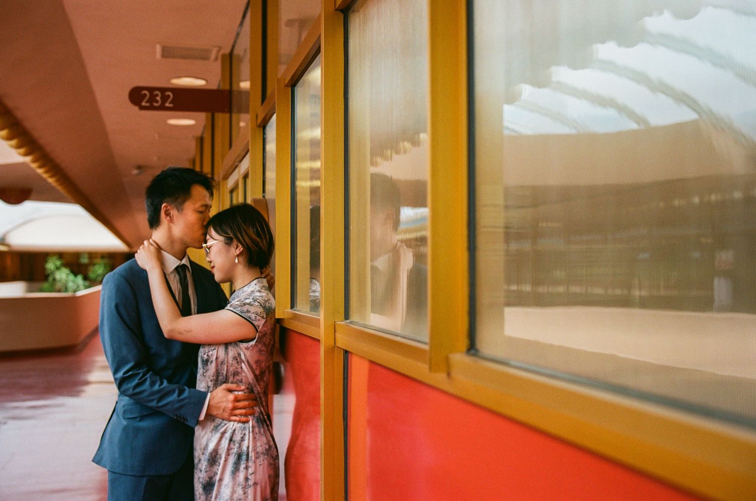 Contemporary interior hallway with yellow and red walls creates geometric wedding photo setting.