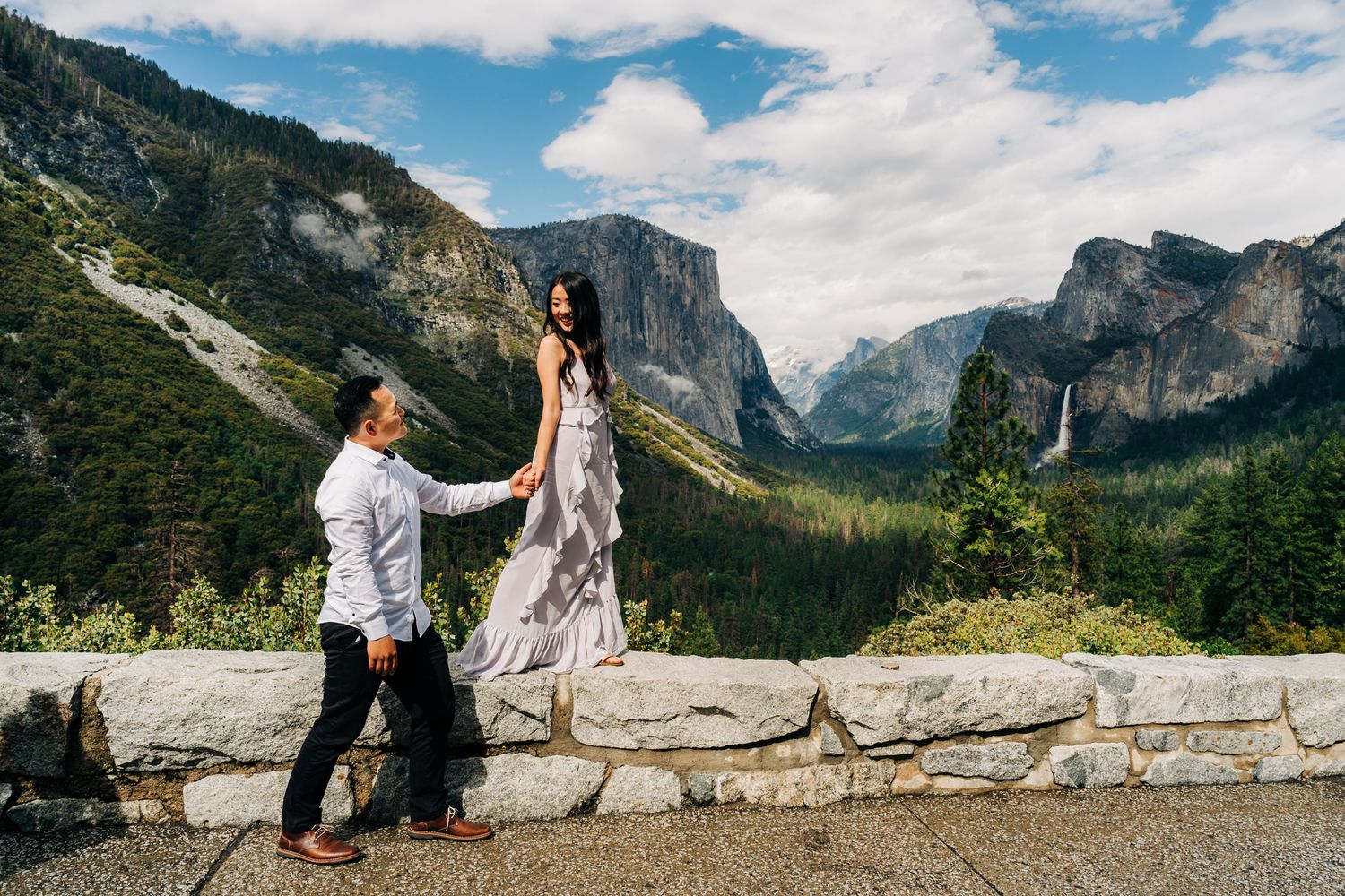 Couple holding hands at Yosemite Tunnel View overlook with El Capitan and Bridalveil Fall.
