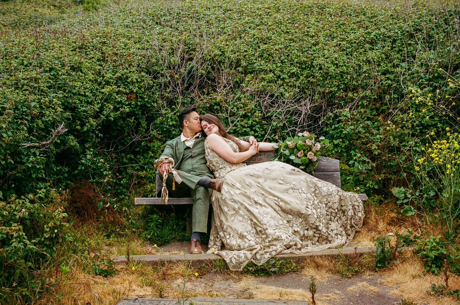 Wedding couple poses on scenic coastal cliffs with natural landscape.