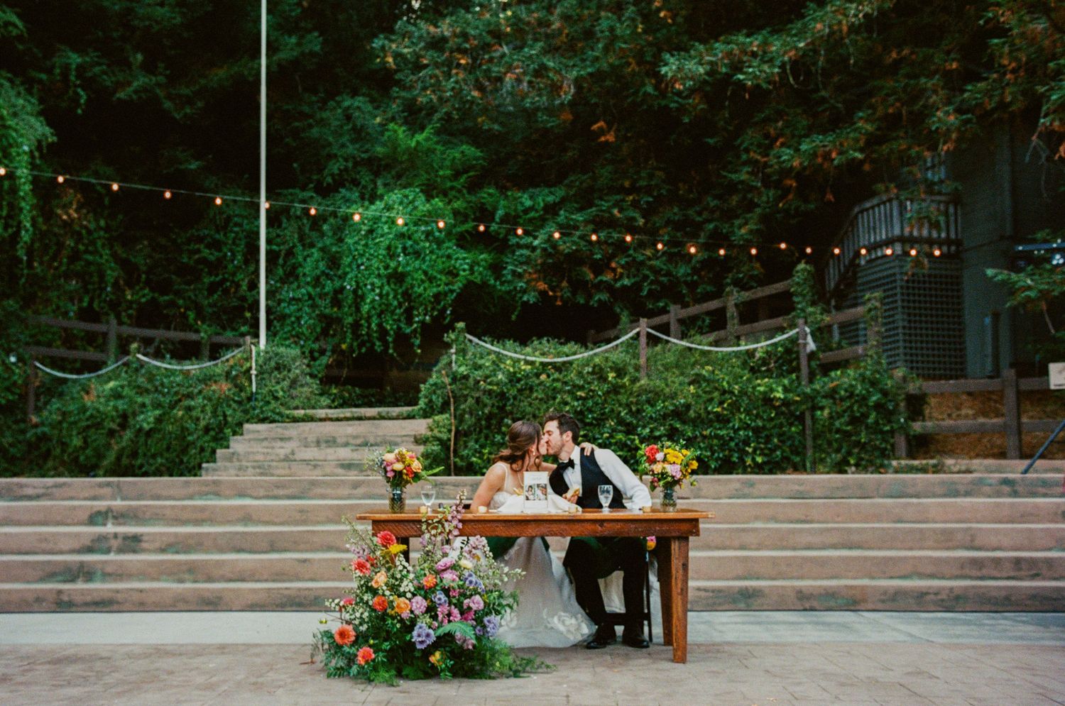 Outdoor wedding ceremony setup with wooden benches and floral arrangements.