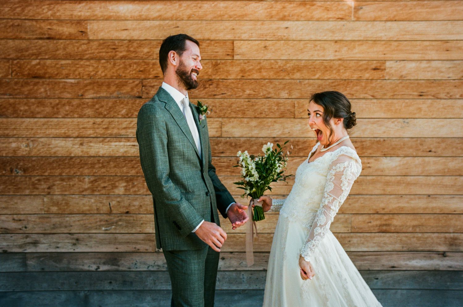 Rustic wooden wall serves as backdrop for intimate wedding portraits.