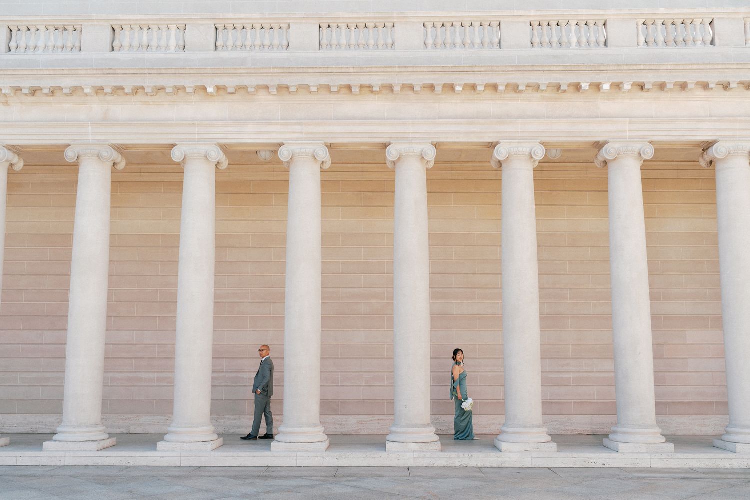 Couple posing apart between grand white marble columns at the Lincoln Memorial in Washington DC.