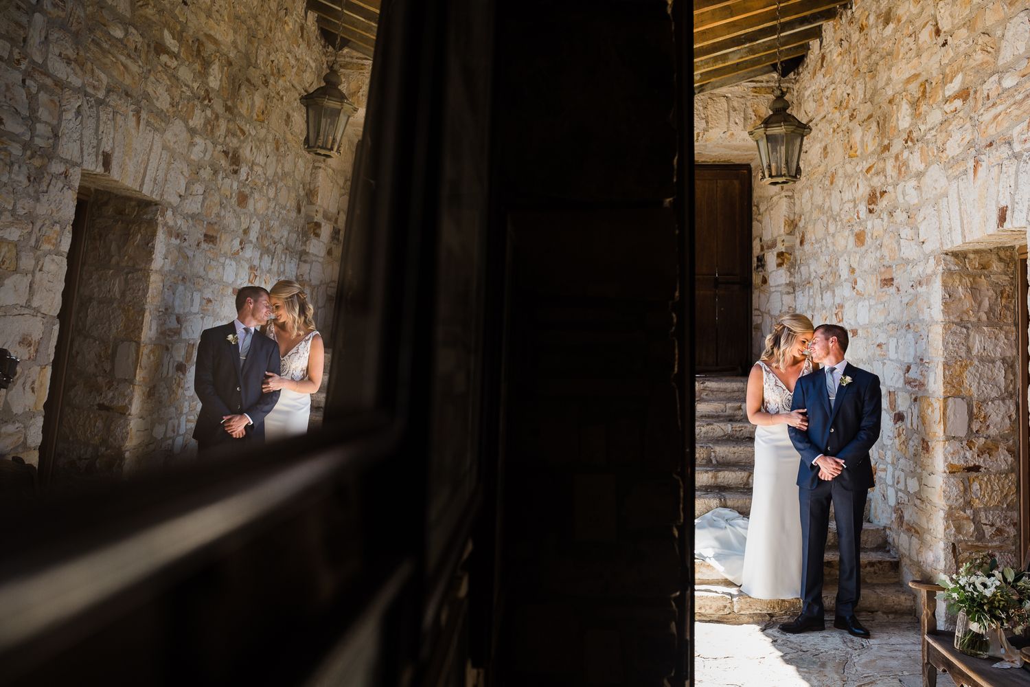 Wedding couple poses for romantic photos in shadowy stone archways.