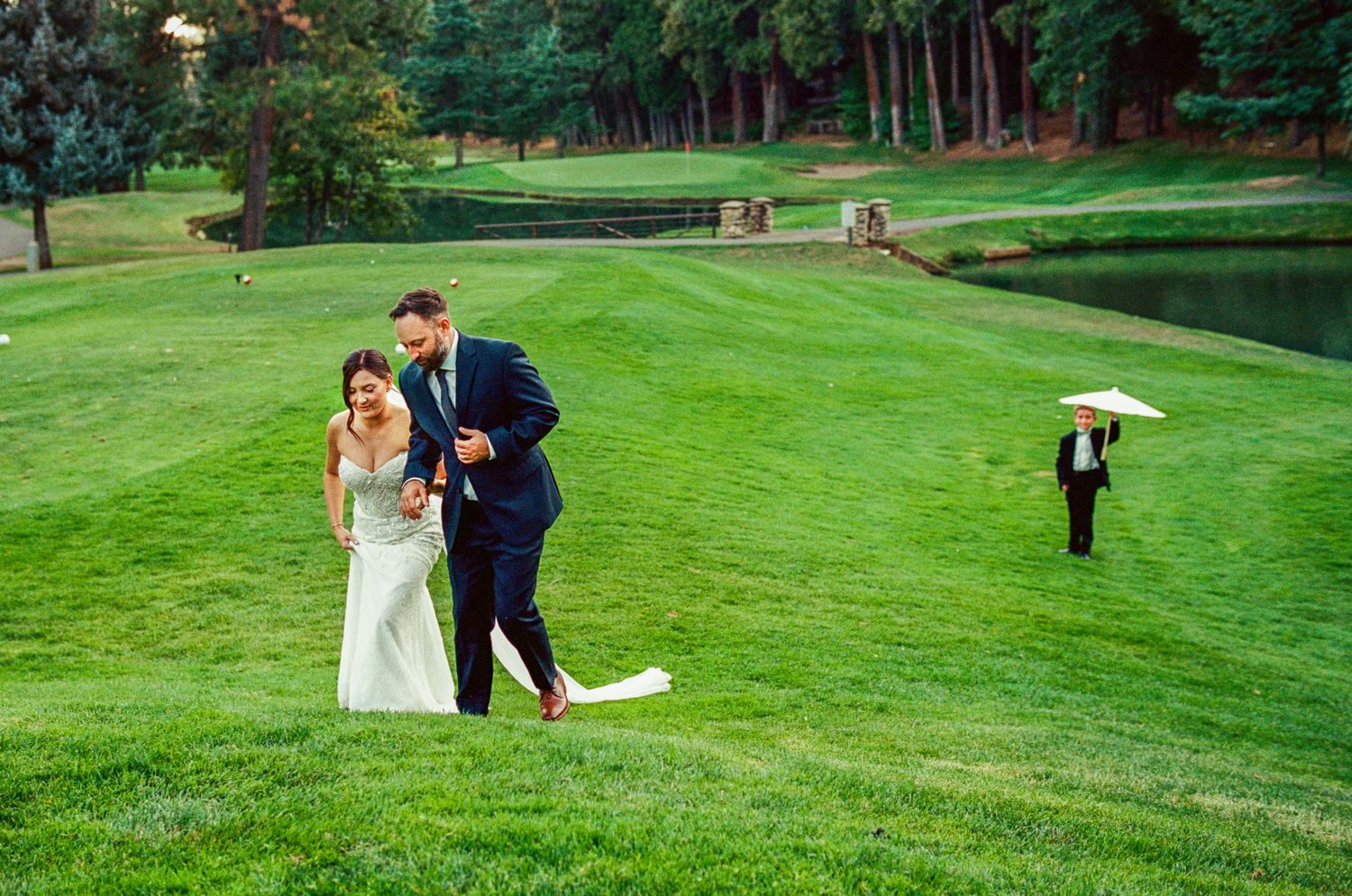 Wedding couple walks across lush green golf course during their photo session.