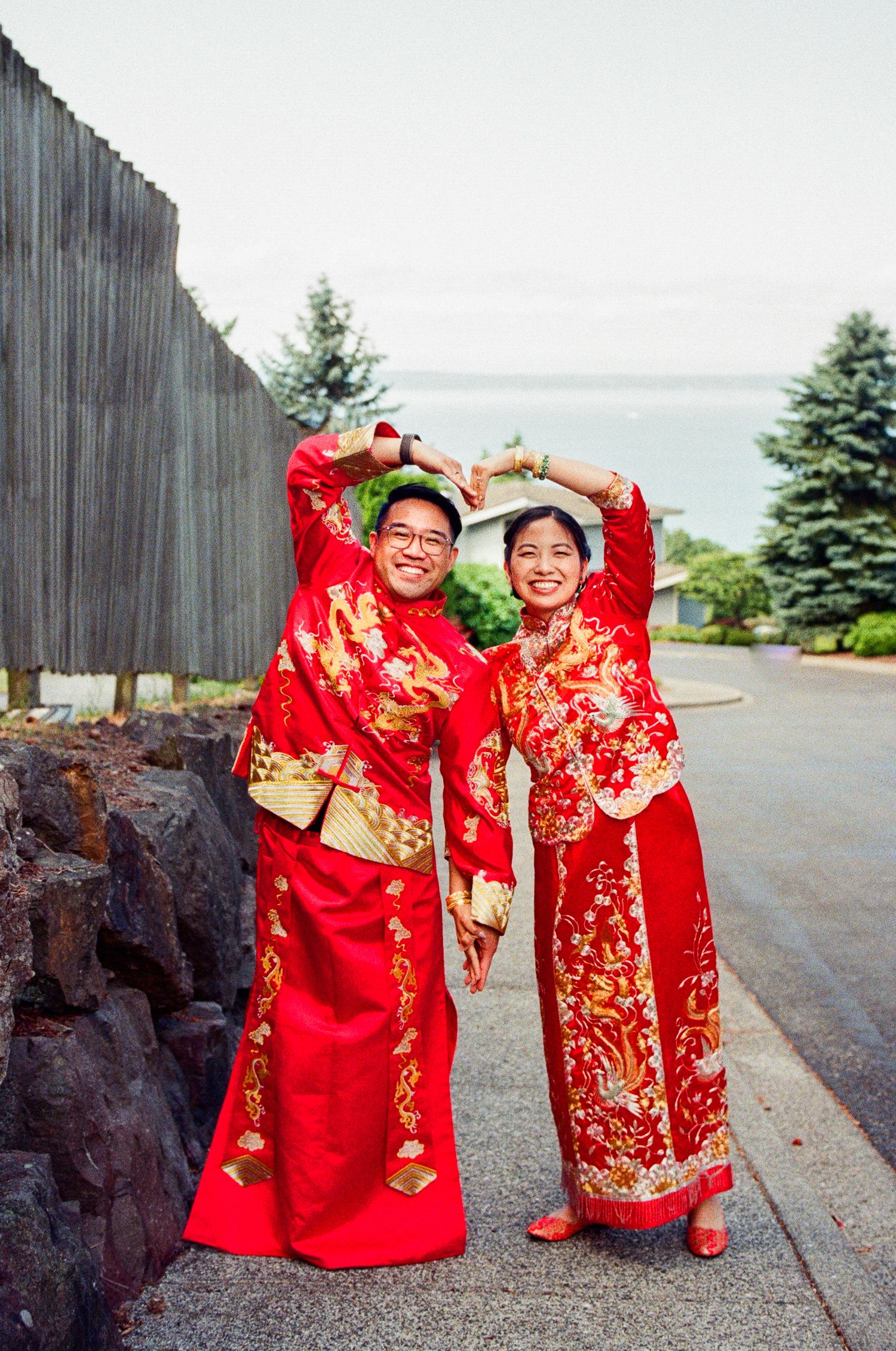 Traditional red Chinese wedding attire with gold embroidery displayed against a scenic outdoor backdrop.