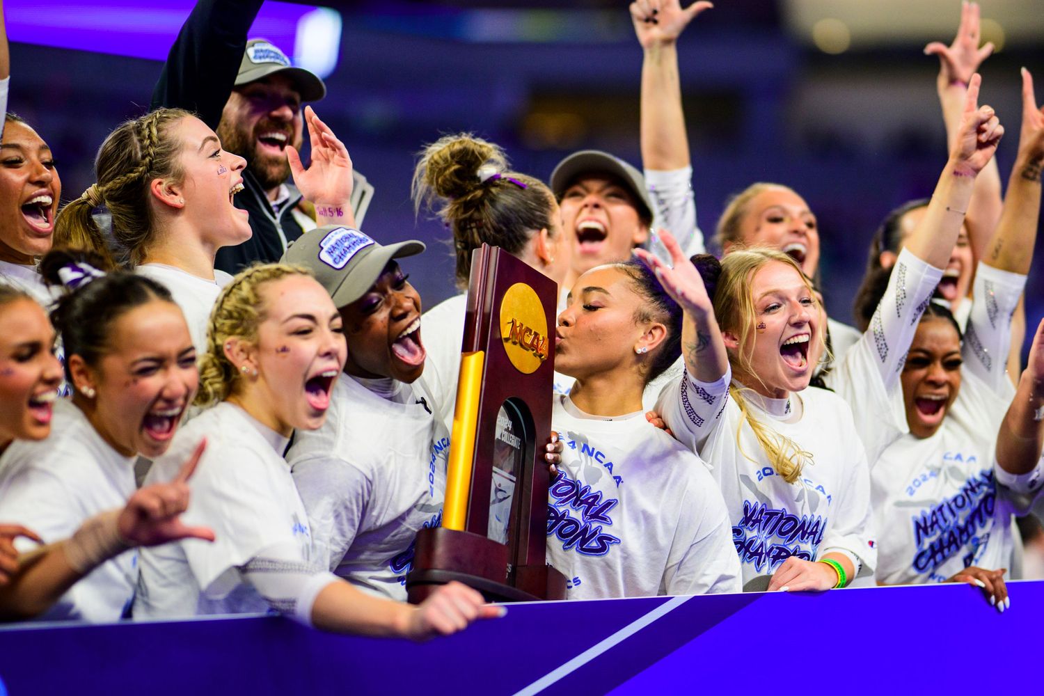 Team celebrates with championship trophy after winning tournament.