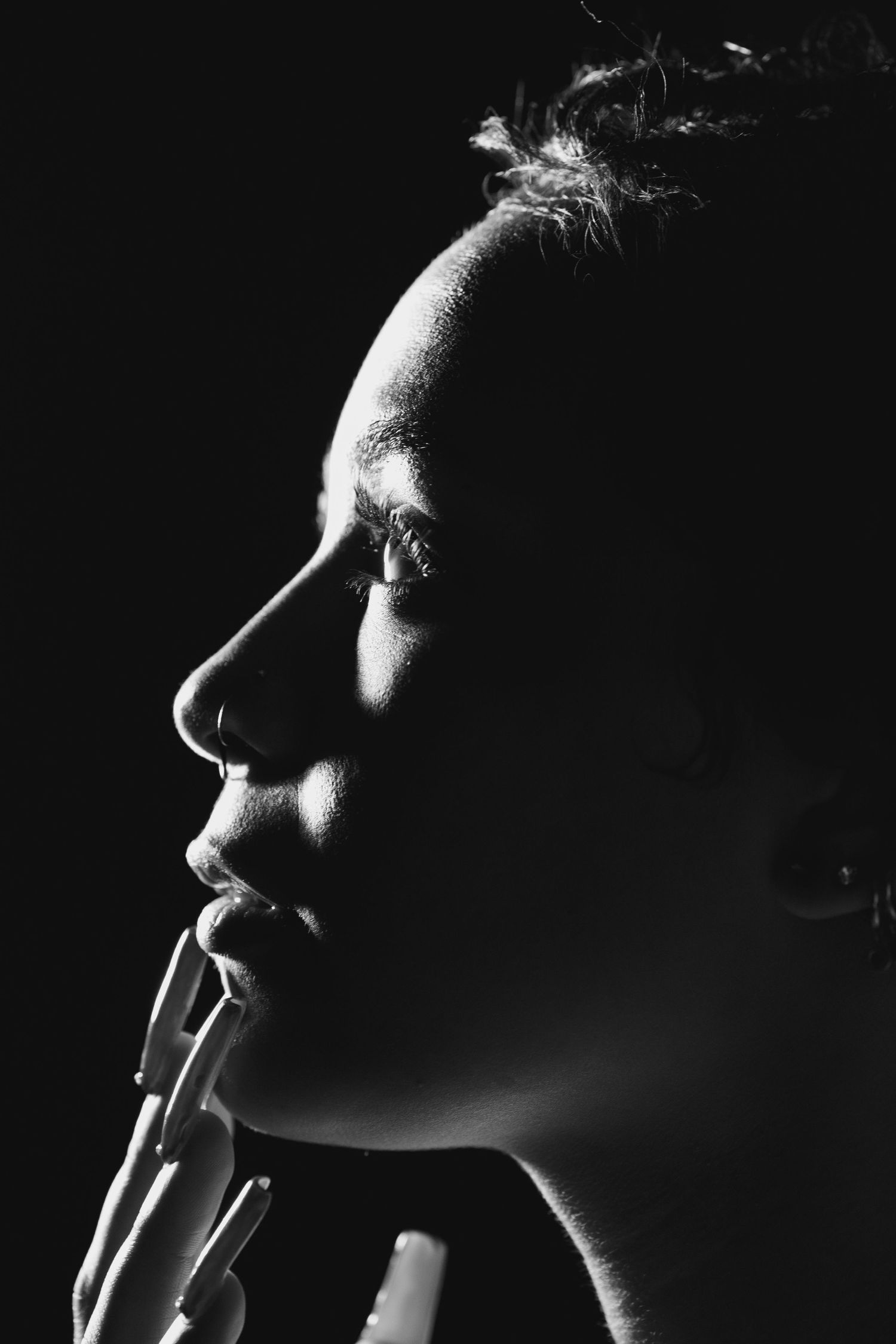 Dramatic side profile portrait in black and white with rim lighting highlighting facial features.