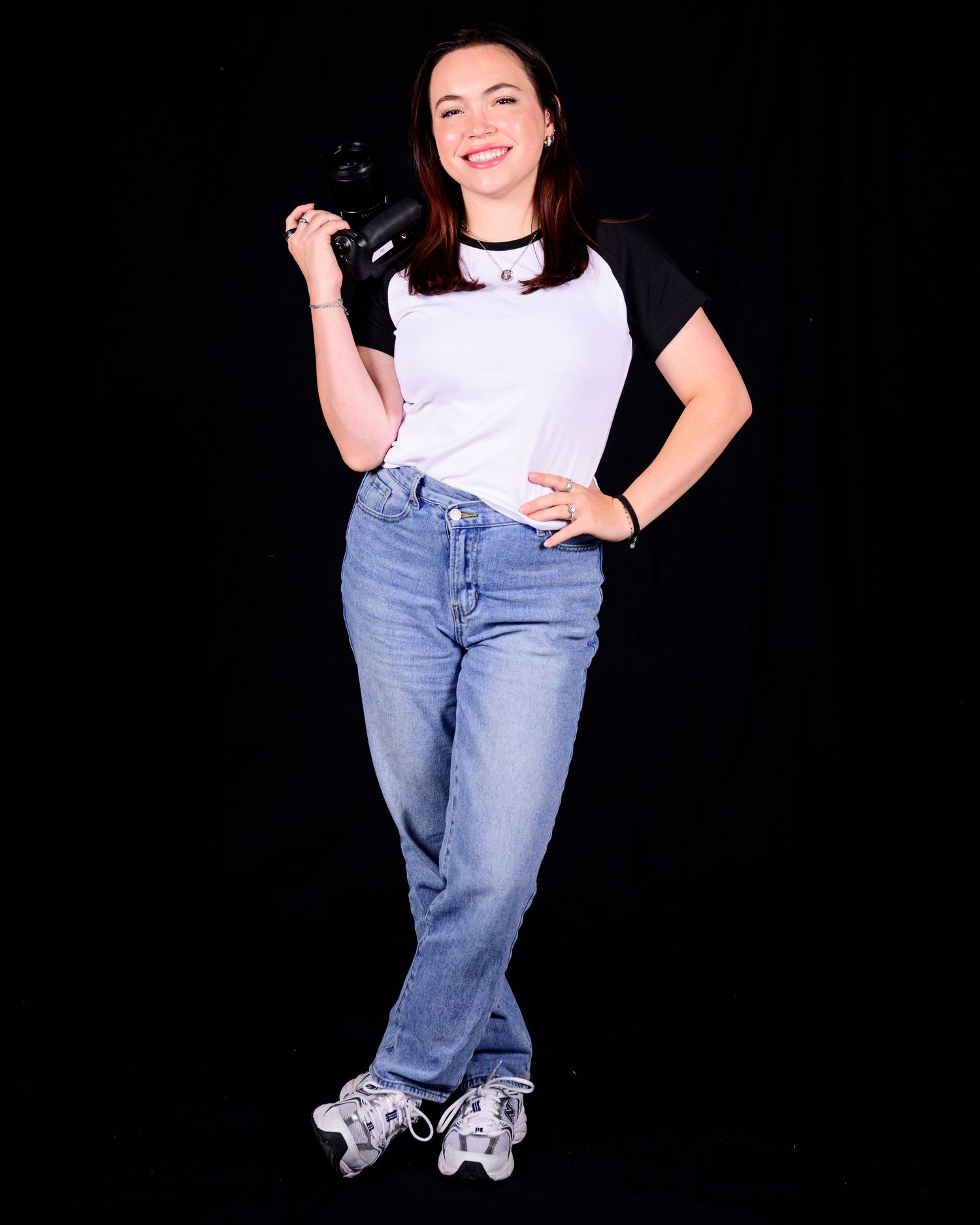 Casual outfit with white and black top, light wash jeans, and roller skates against a black background.
