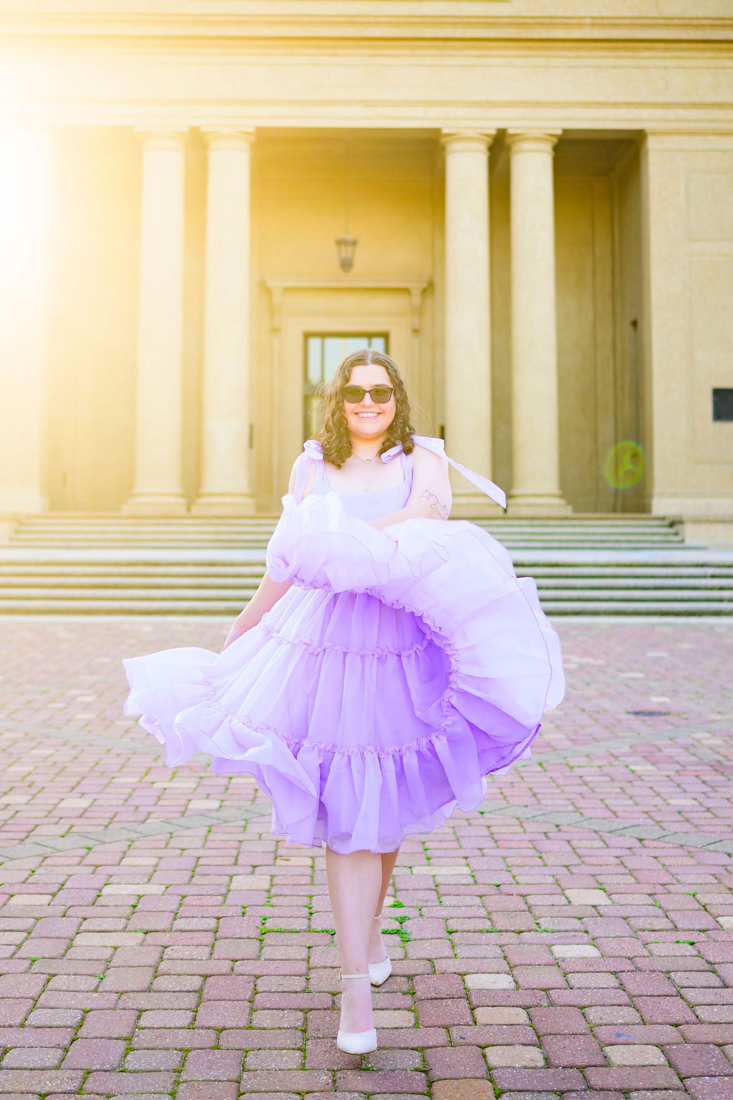 Person twirling in a lavender tulle dress in front of classic architectural columns.
