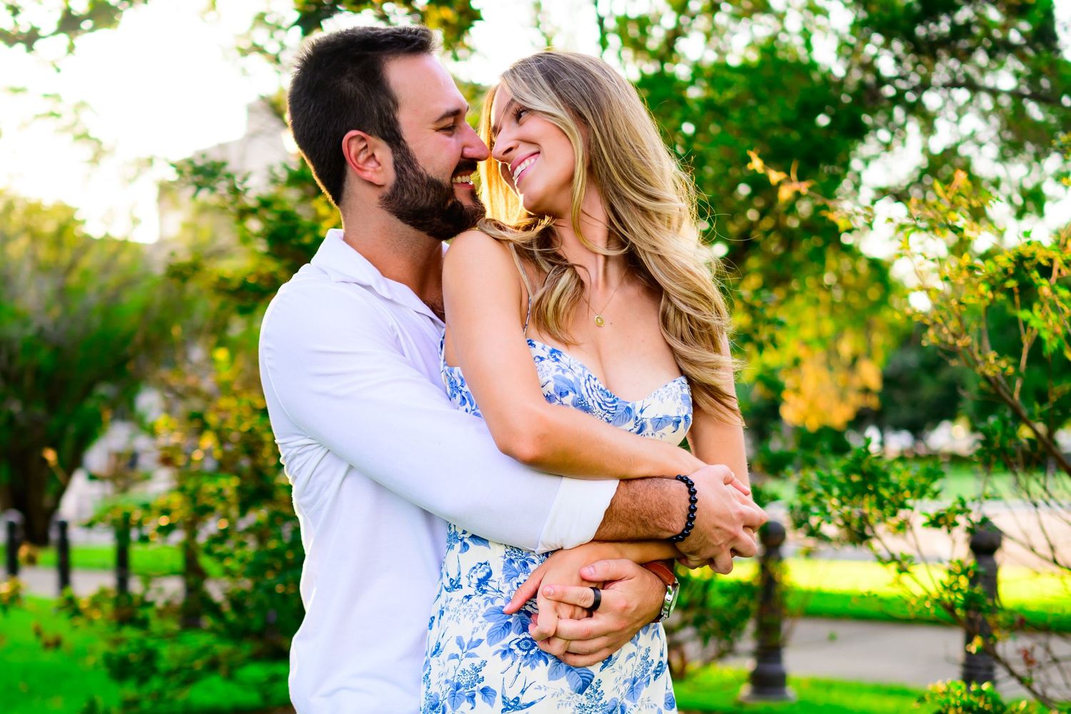 Couple in coordinating blue and white outfits embrace in a sunny garden setting.