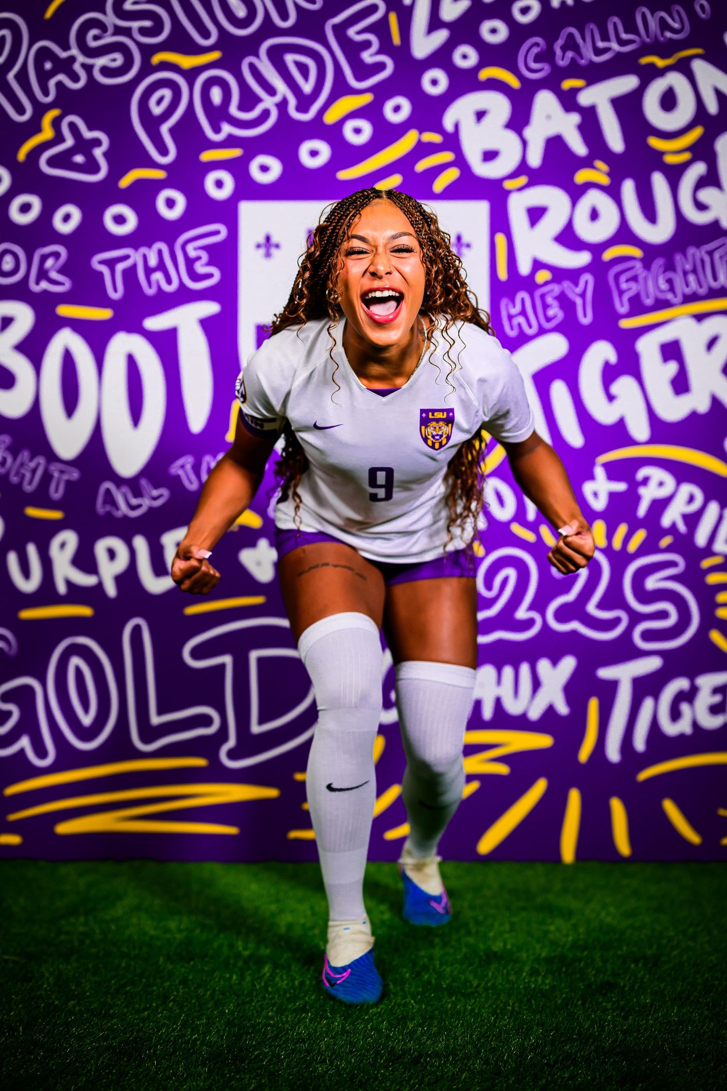 Energetic soccer player celebrating in front of purple wall with fan artwork and text.