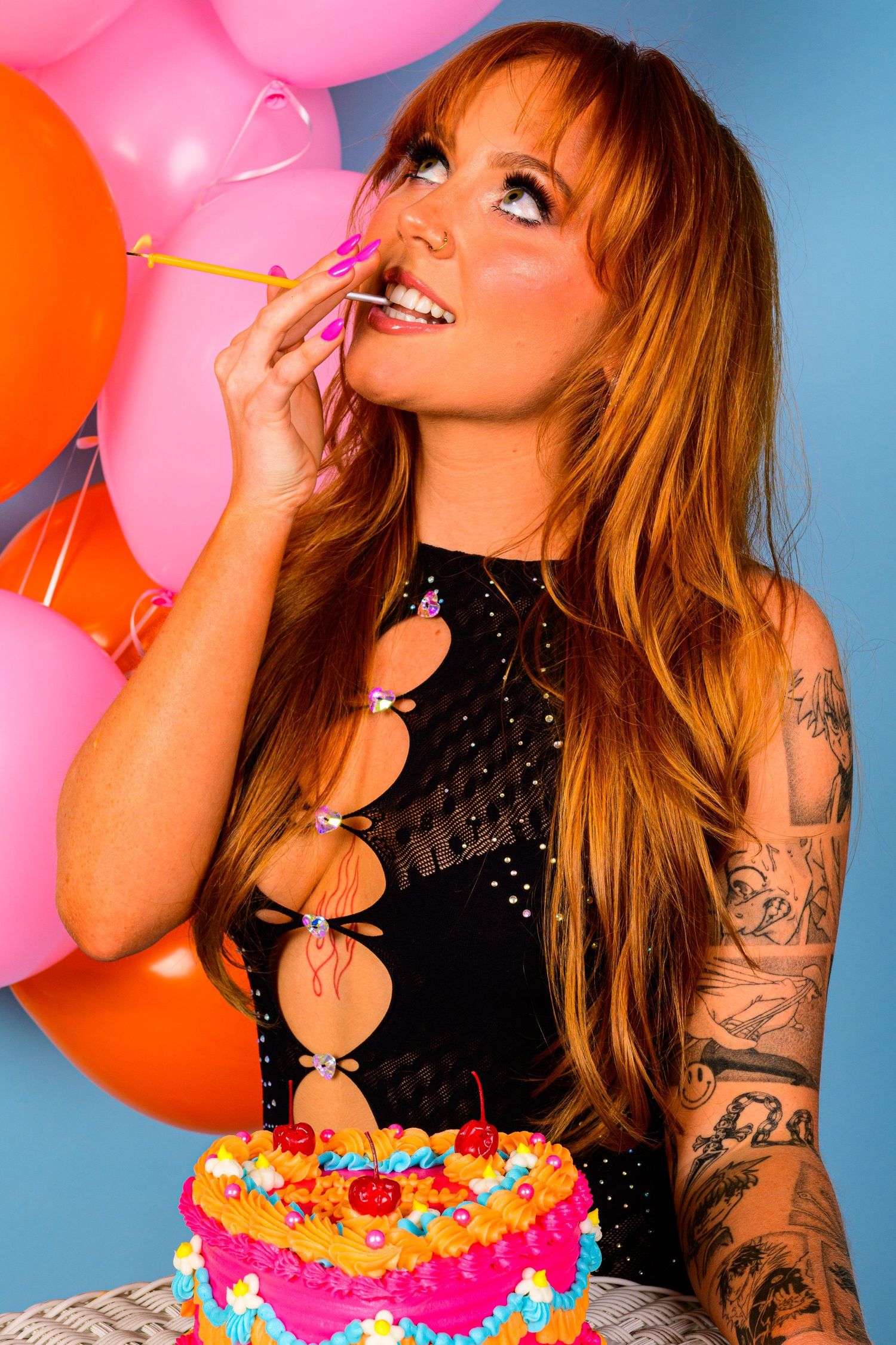 Portrait with pink balloons and colorful cake against blue background.