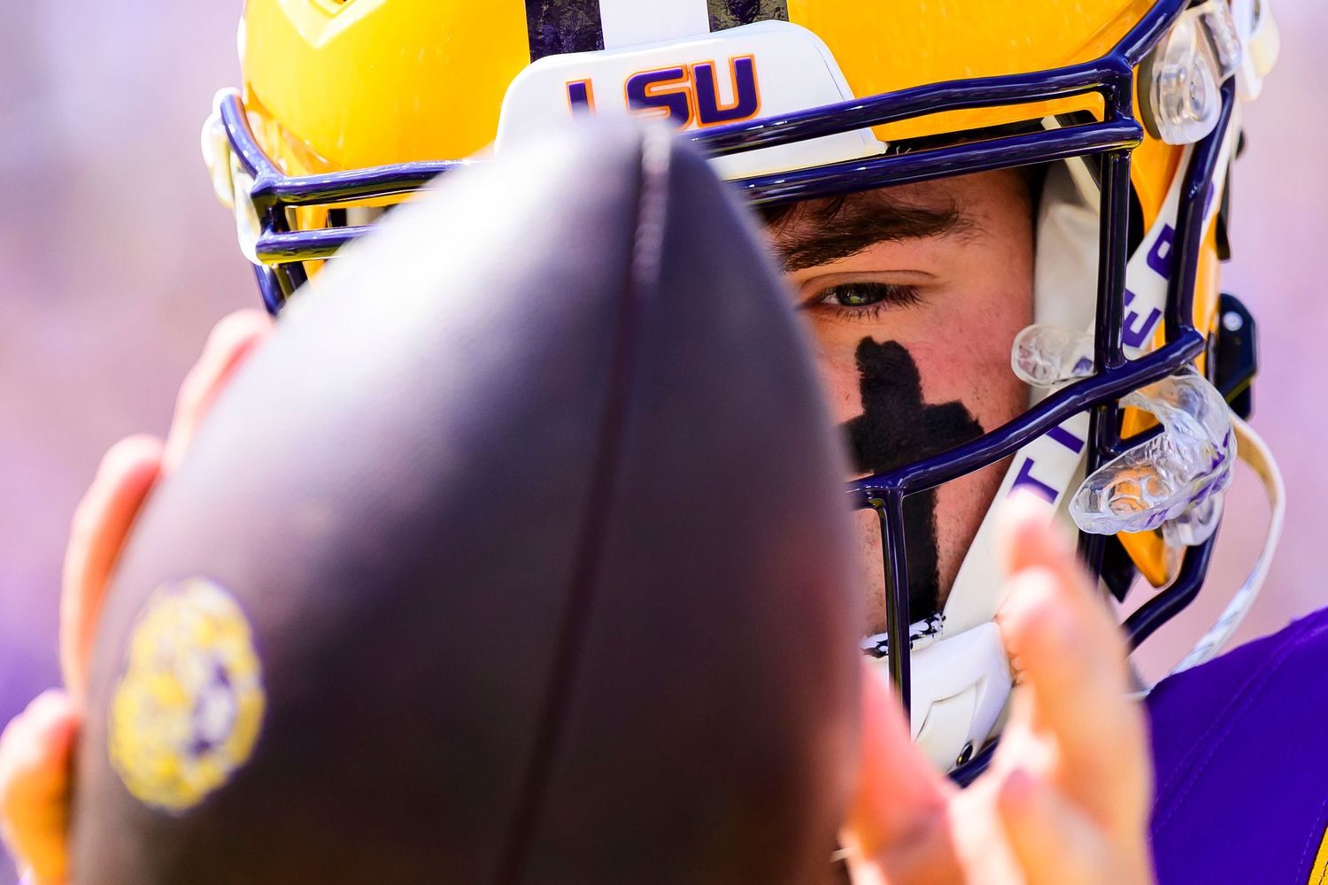 Close-up shot of a football player wearing a yellow and purple LSU football helmet.
