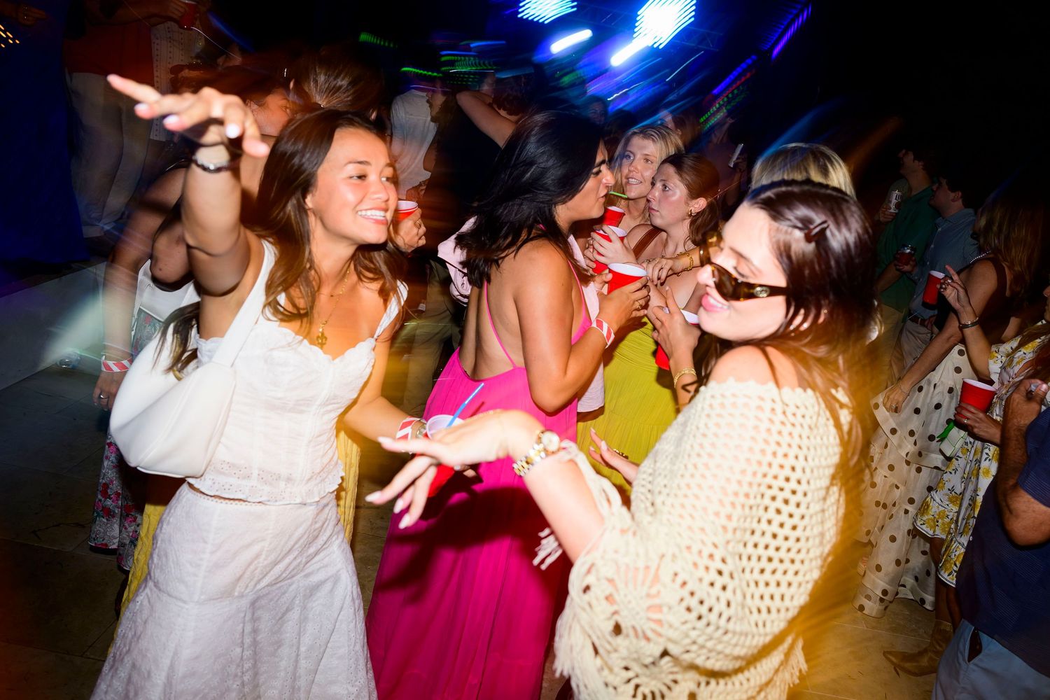 Group of party-goers dancing and having fun under blue lighting at nightclub.