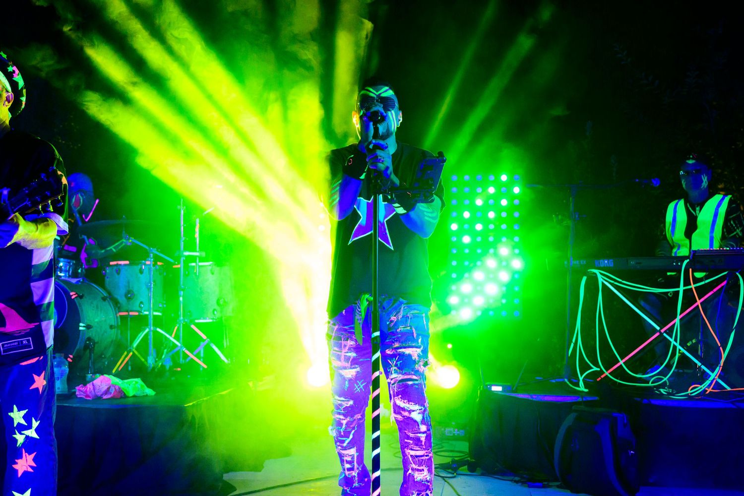Performer on stage with bright green lighting effects and neon star decorations.