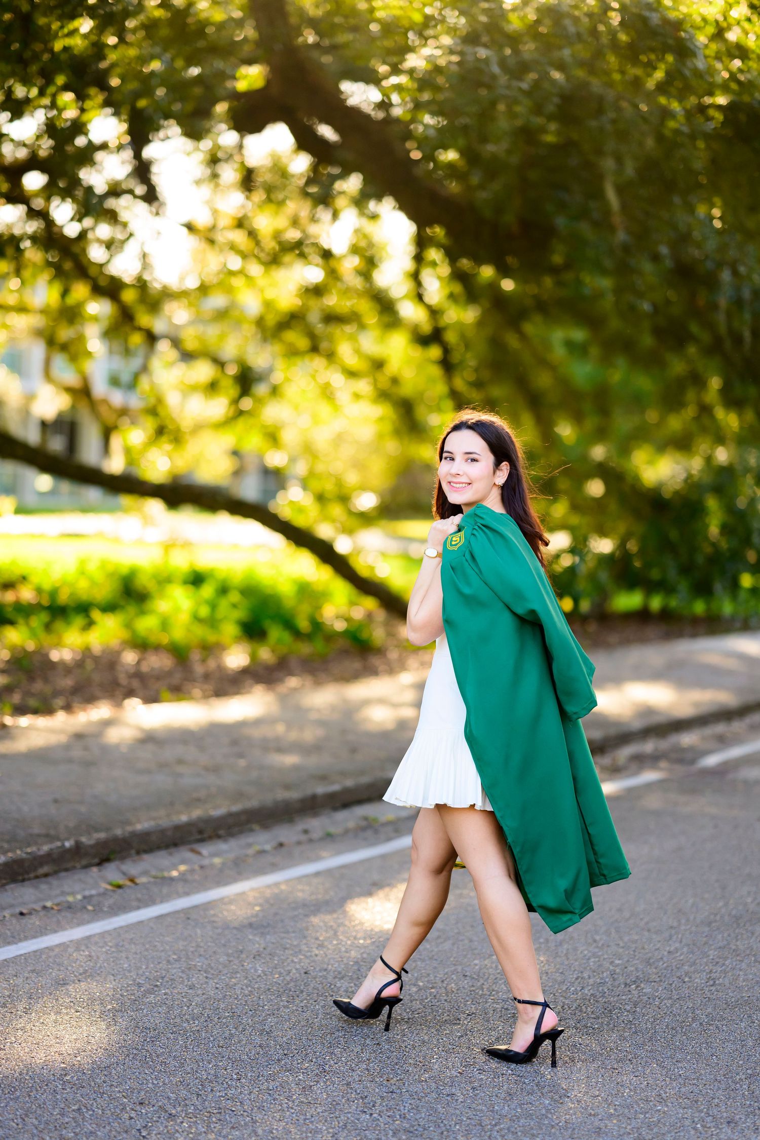 Fashion photo of woman in green coat and white dress walking on street.