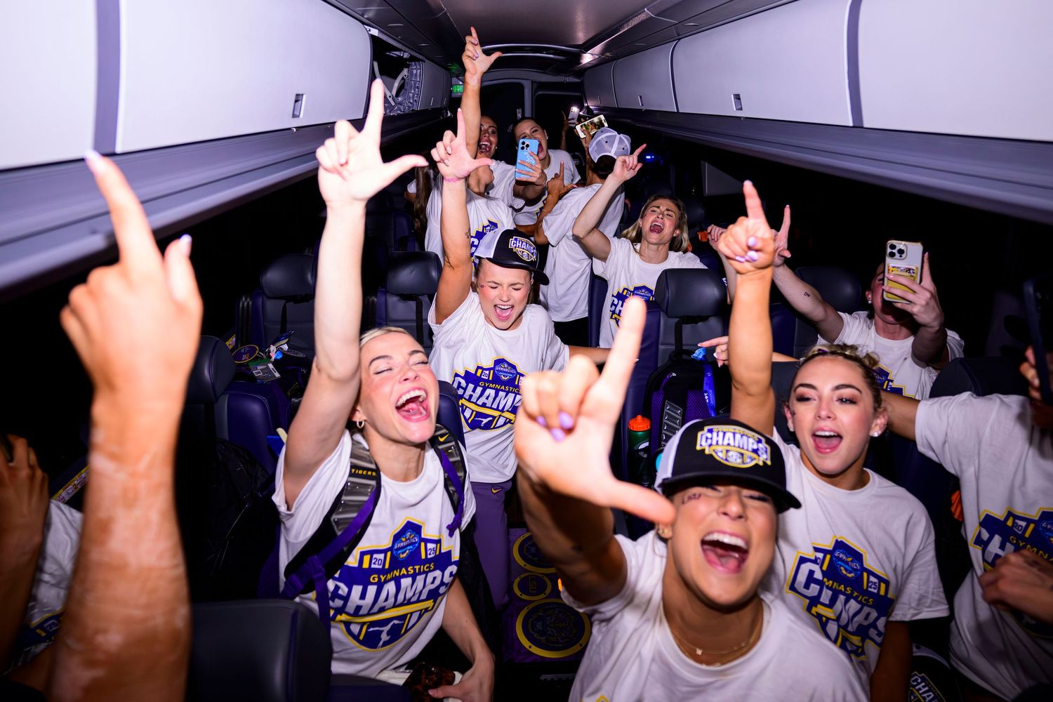 Baseball players celebrate enthusiastically in a team bus with raised arms and excited cheers after winning a game.