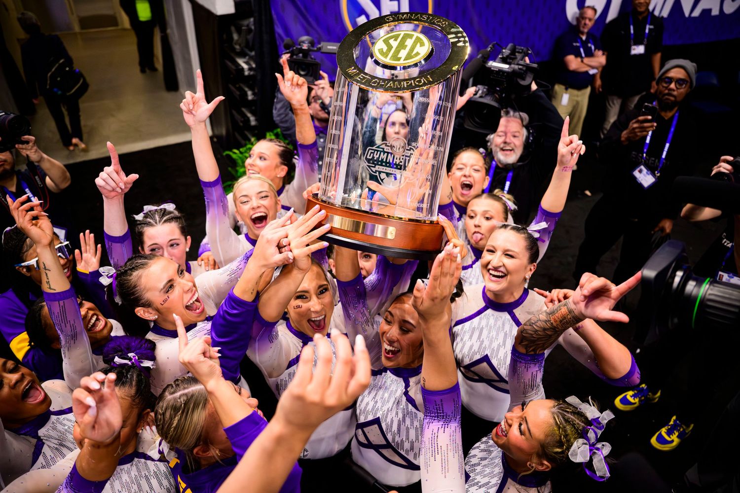 Championship trophy celebration with team members cheering and holding up trophy in victory.