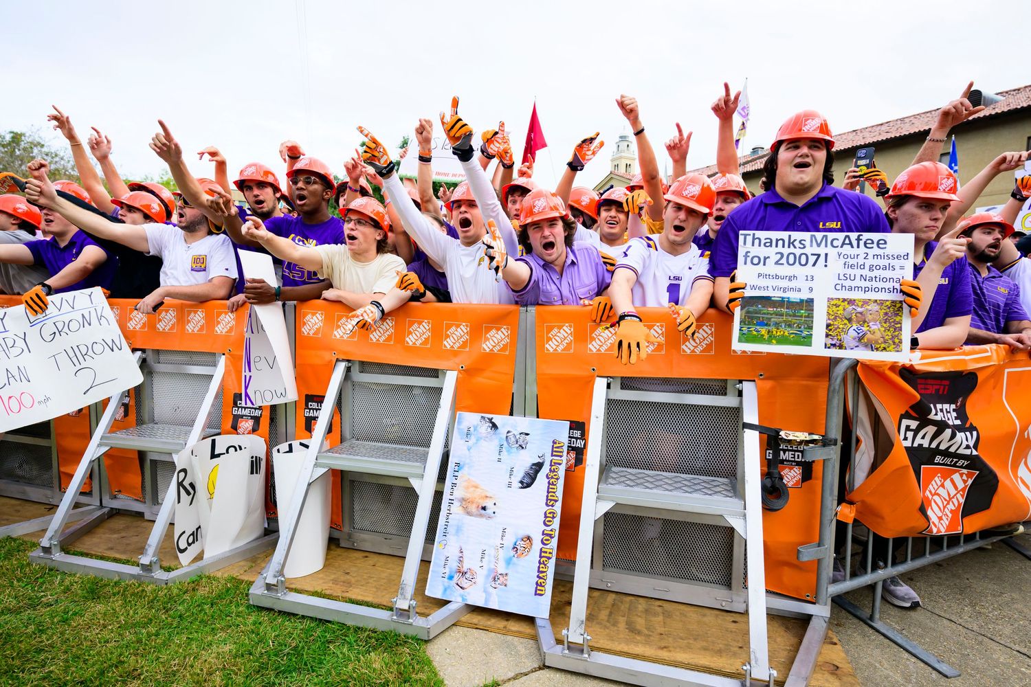 Enthusiastic LSU fans cheering behind barriers at sporting event.