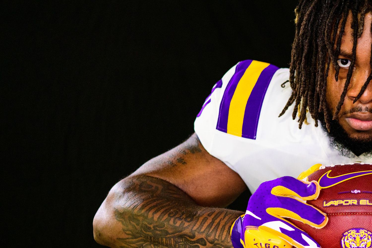 Close-up of LSU football uniform showing purple and gold stripes with football.
