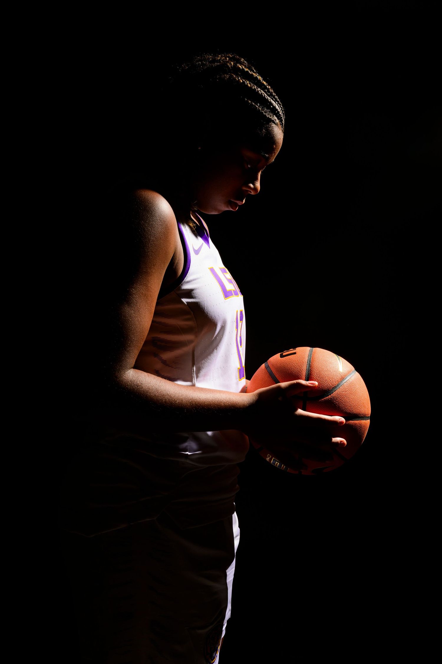 Dramatic silhouette of basketball player holding ball in moody lighting.