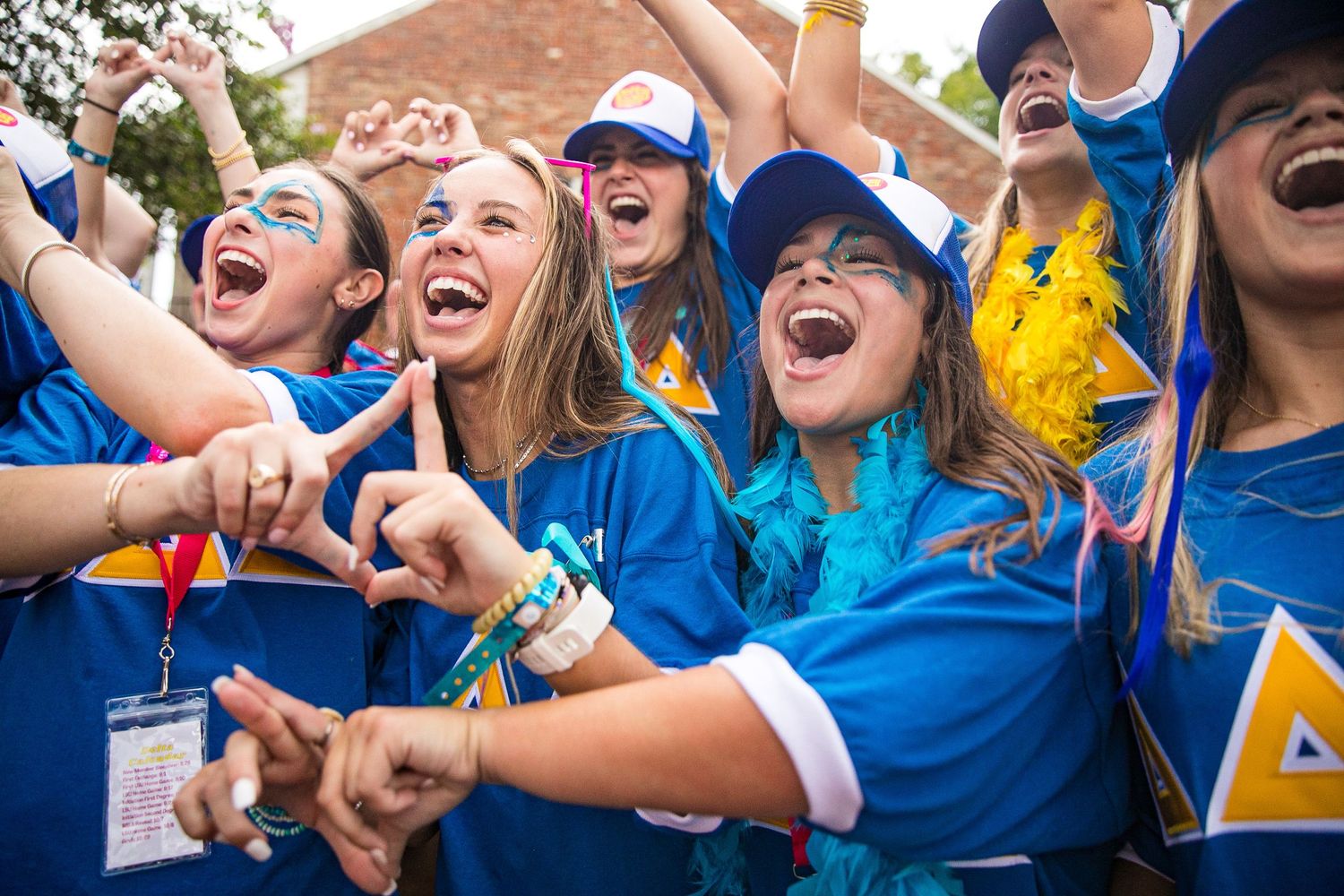 Enthusiastic group in blue shirts cheering at outdoor event.