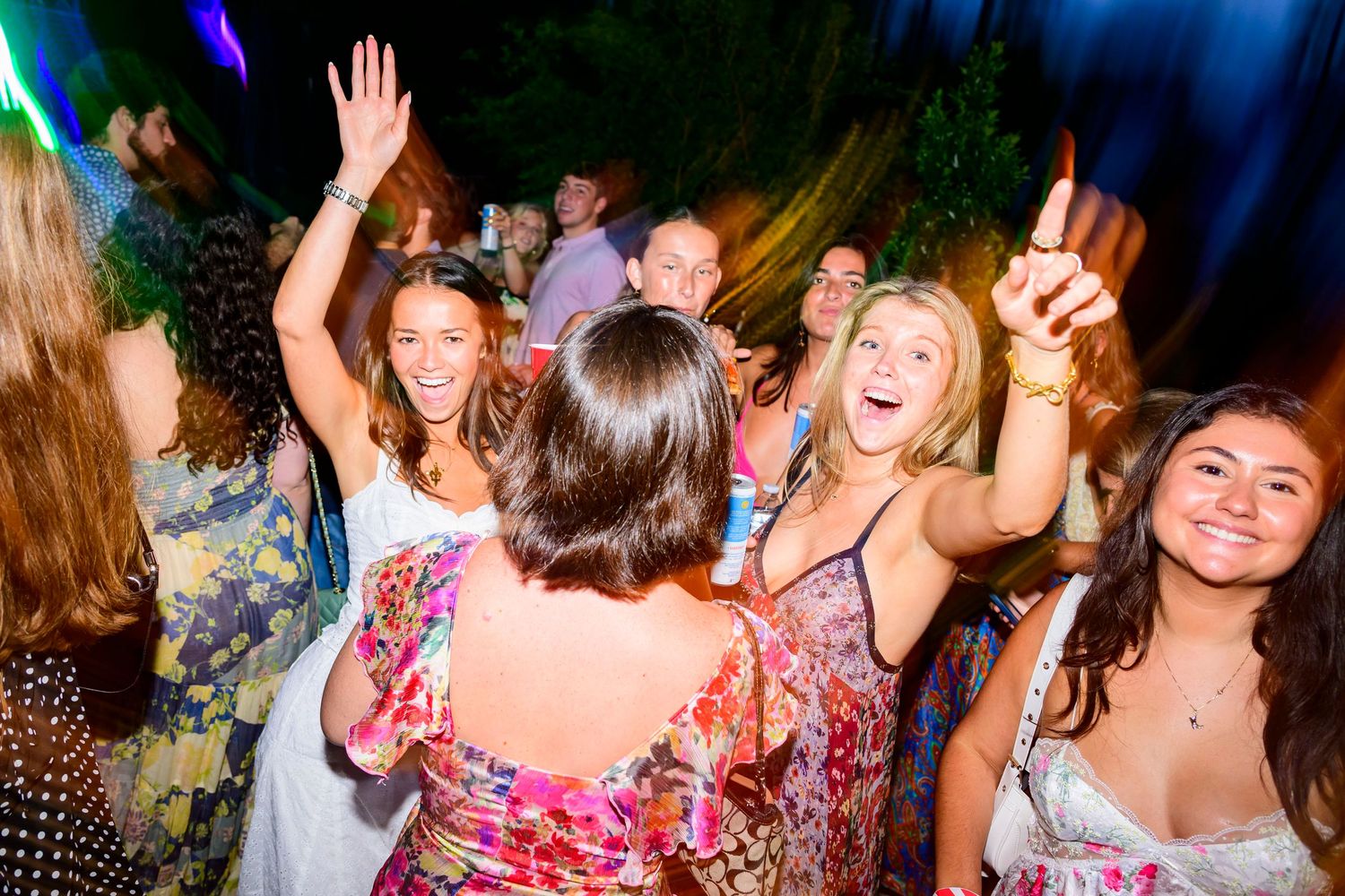 People dancing and celebrating at a lively nighttime party with colorful lights and decorations.